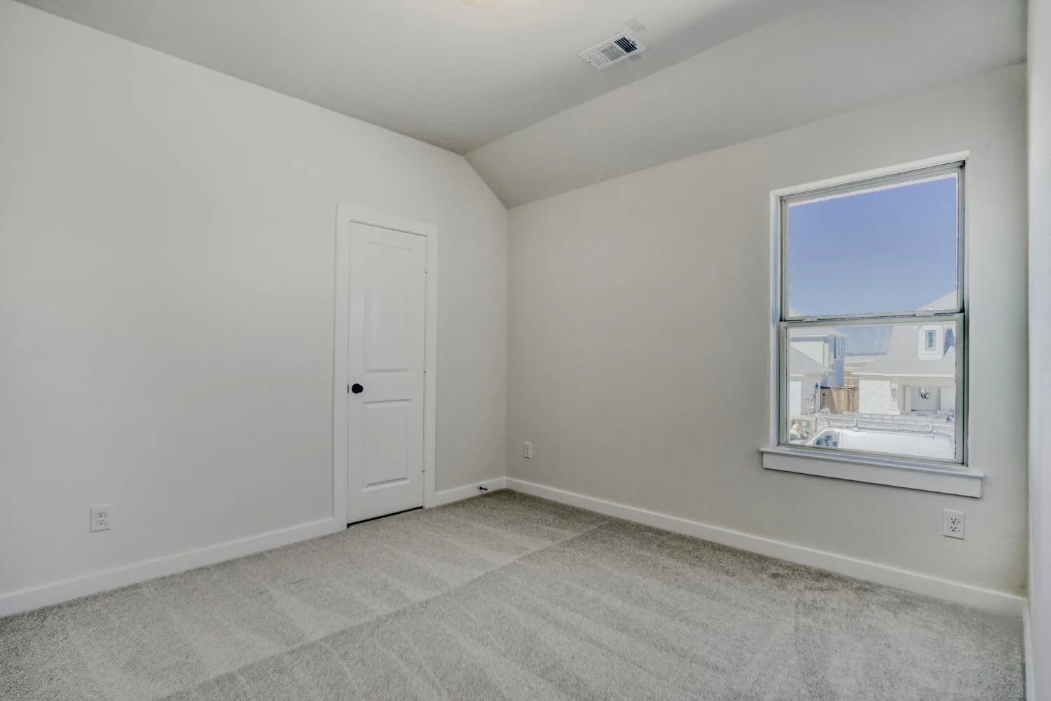 Spare room featuring light carpet and vaulted ceiling