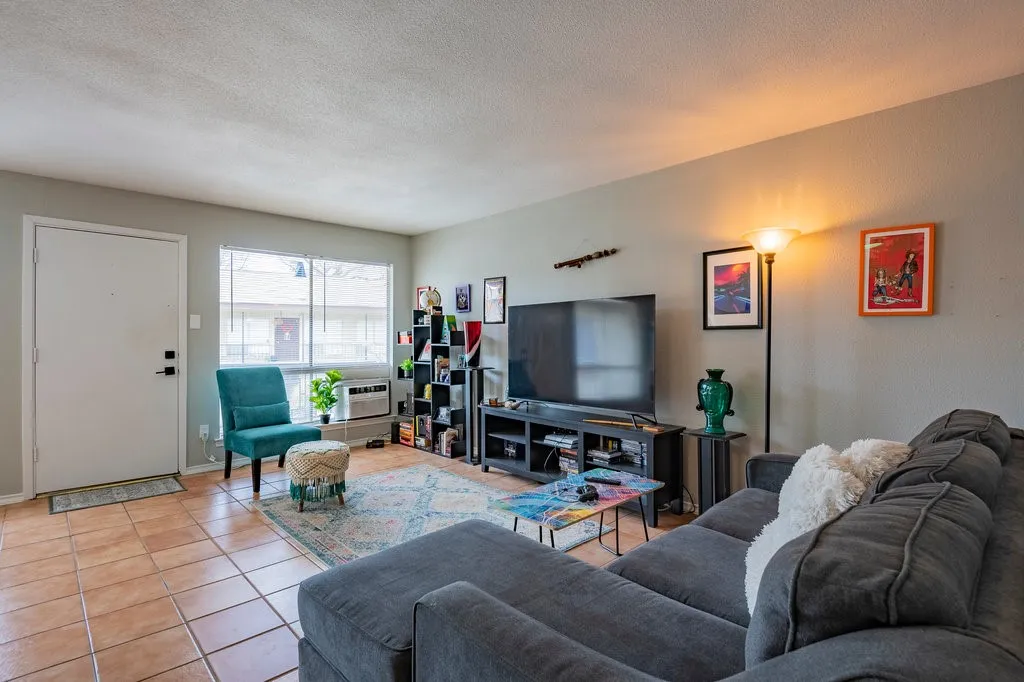 Tiled living area featuring a textured ceiling and baseboards
