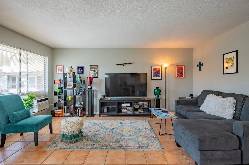 Living area with a textured ceiling, tile patterned flooring, and an AC wall unit