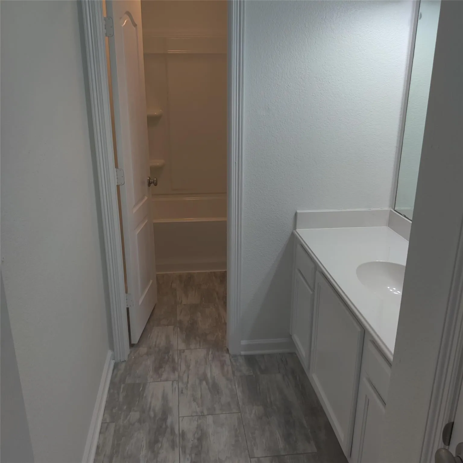 Full bathroom featuring vanity, a textured wall, and shower / tub combination