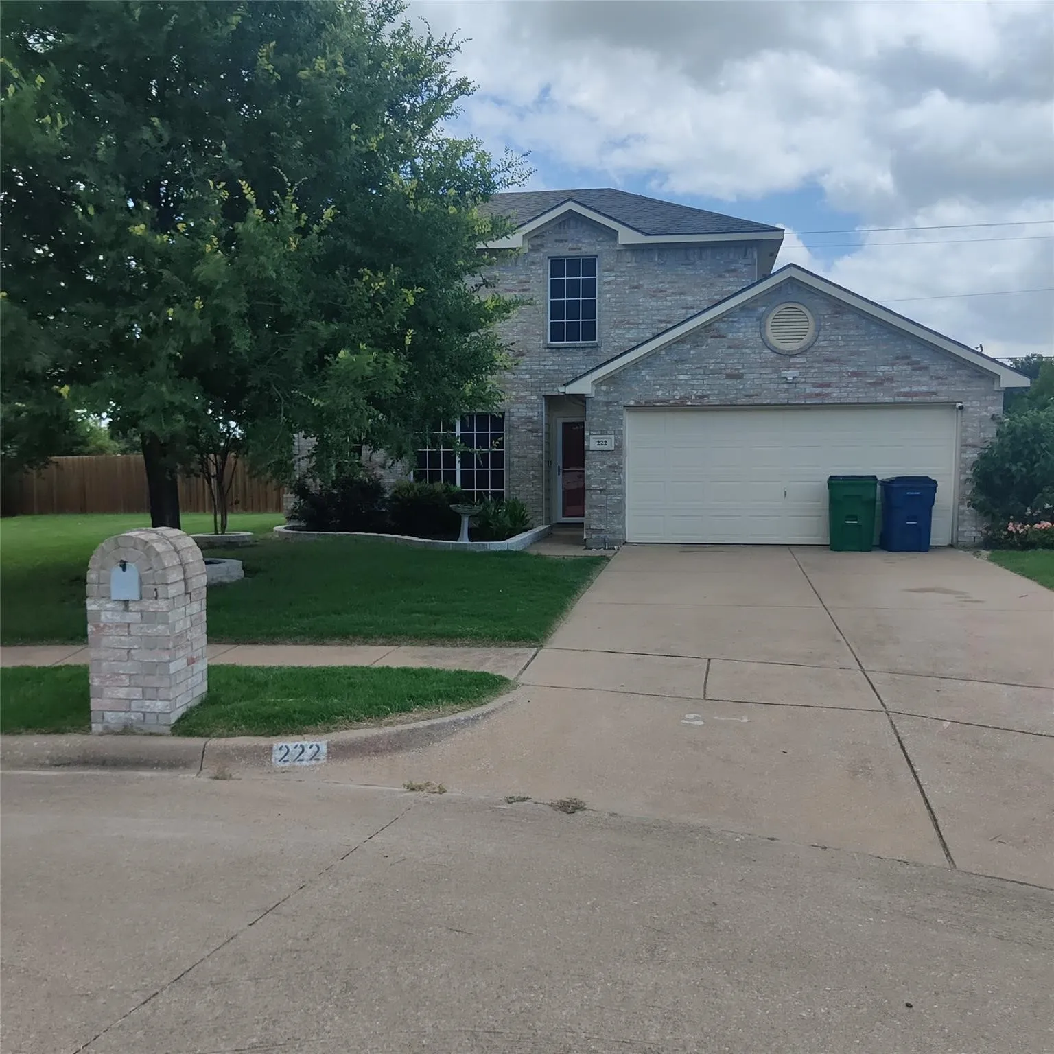Traditional home with an attached garage, driveway, and brick siding