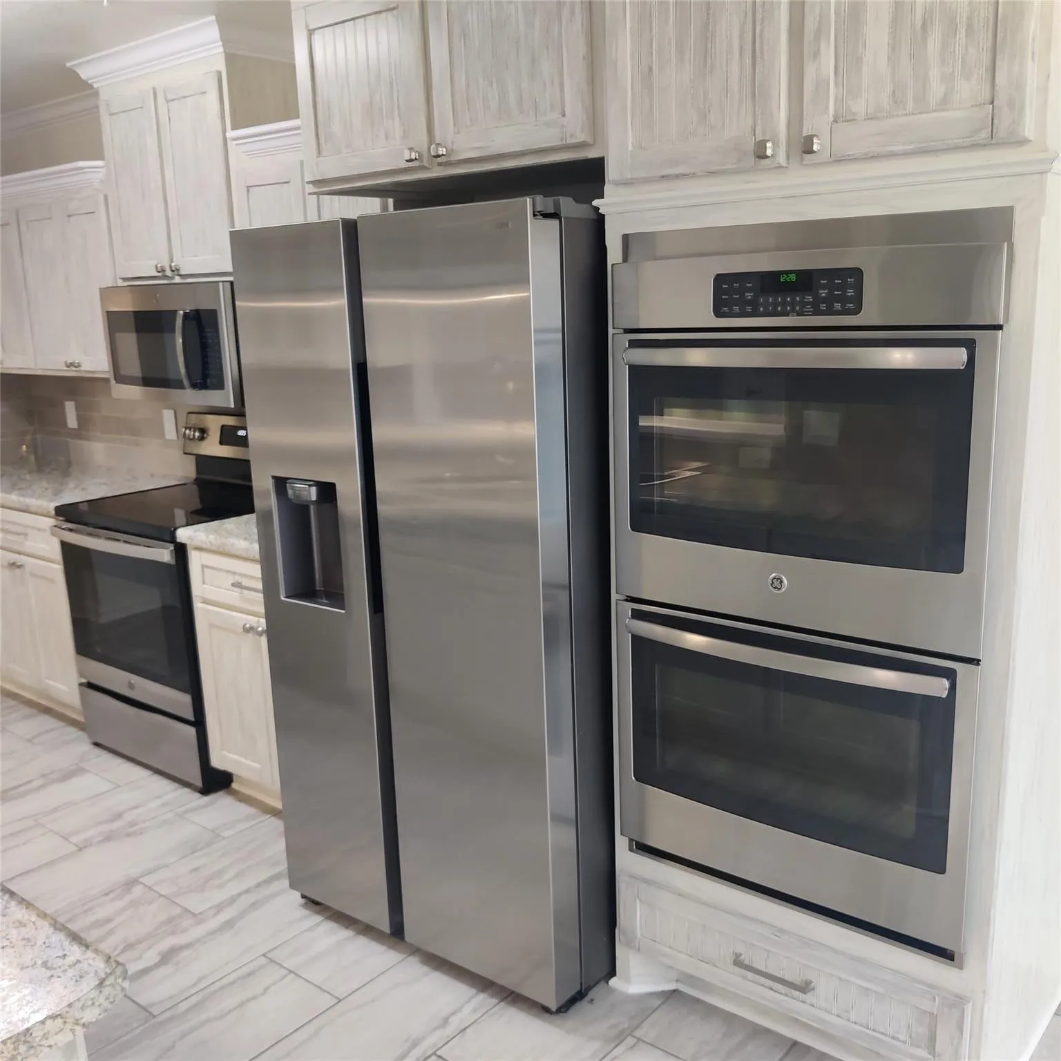 Kitchen featuring appliances with stainless steel finishes, ornamental molding, backsplash, and light stone countertops