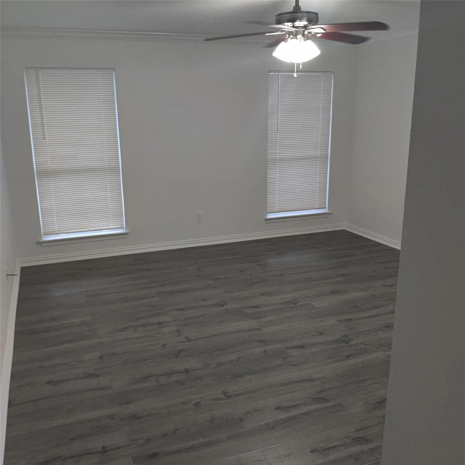 Empty room with ornamental molding, dark wood-style flooring, and ceiling fan
