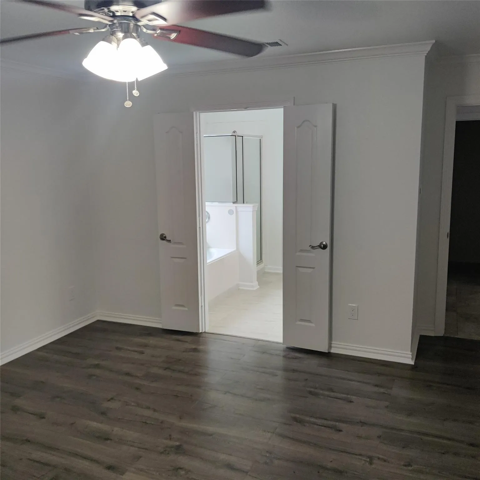 Unfurnished bedroom with crown molding, ceiling fan, and dark wood finished floors