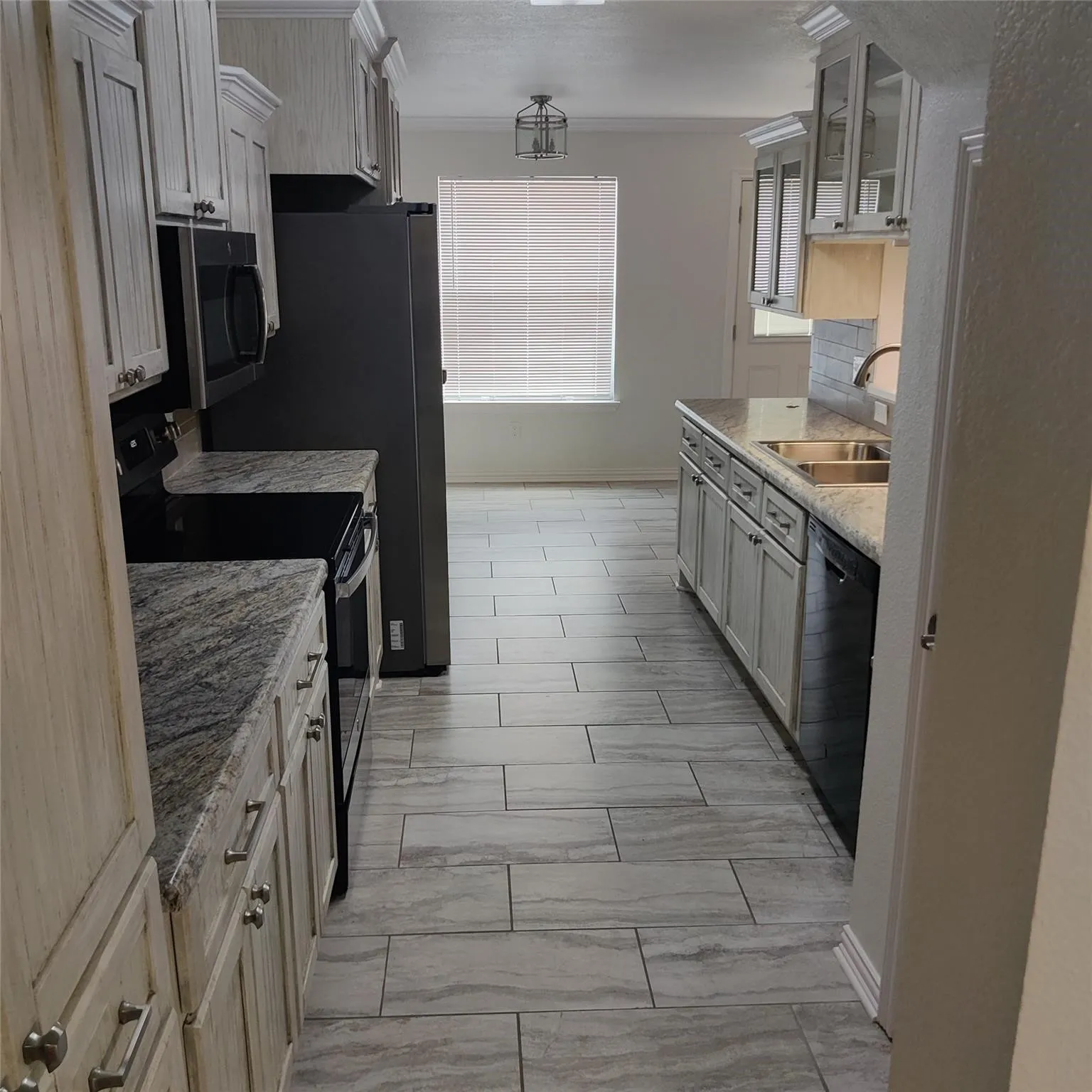 Kitchen featuring black appliances, glass insert cabinets, crown molding, and light stone countertops