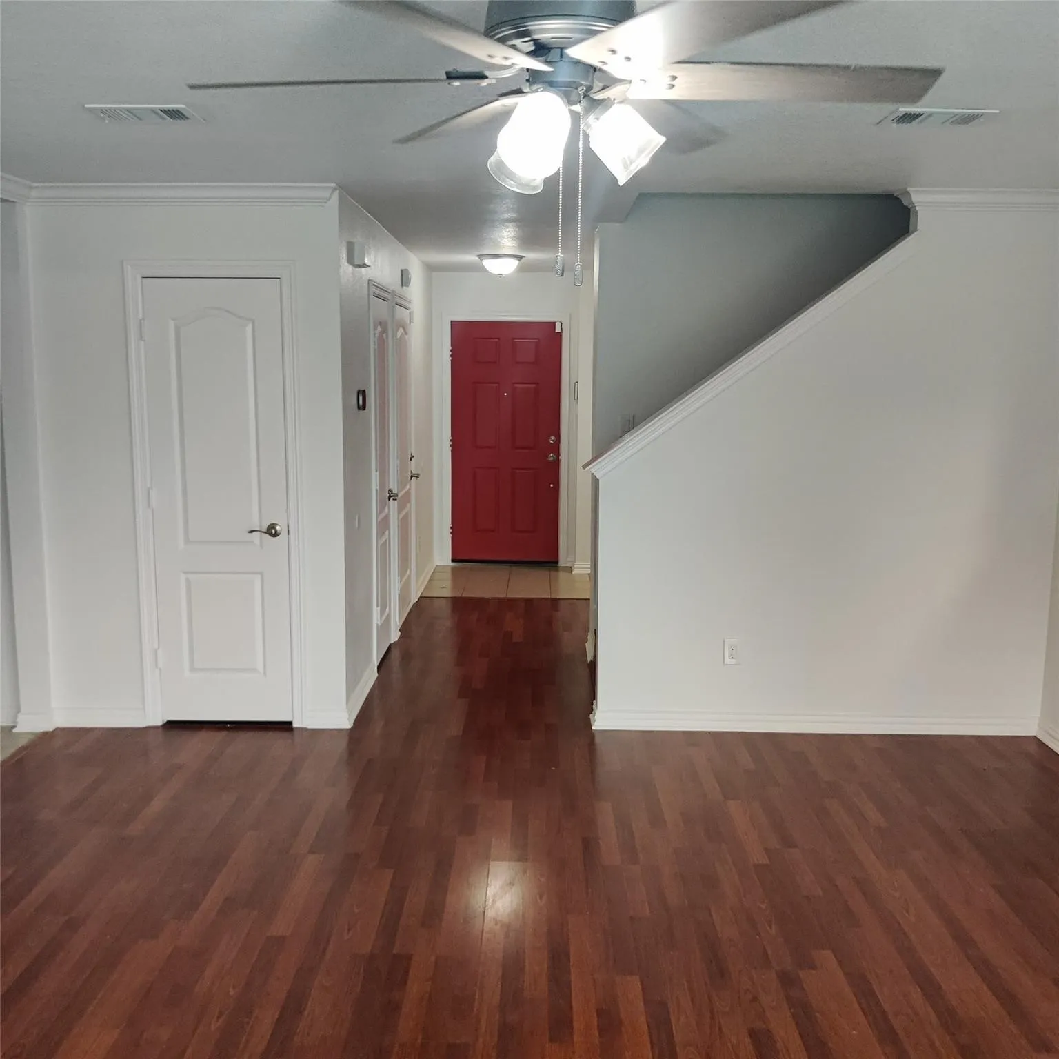 Foyer with a ceiling fan, ornamental molding, and dark wood-style flooring
