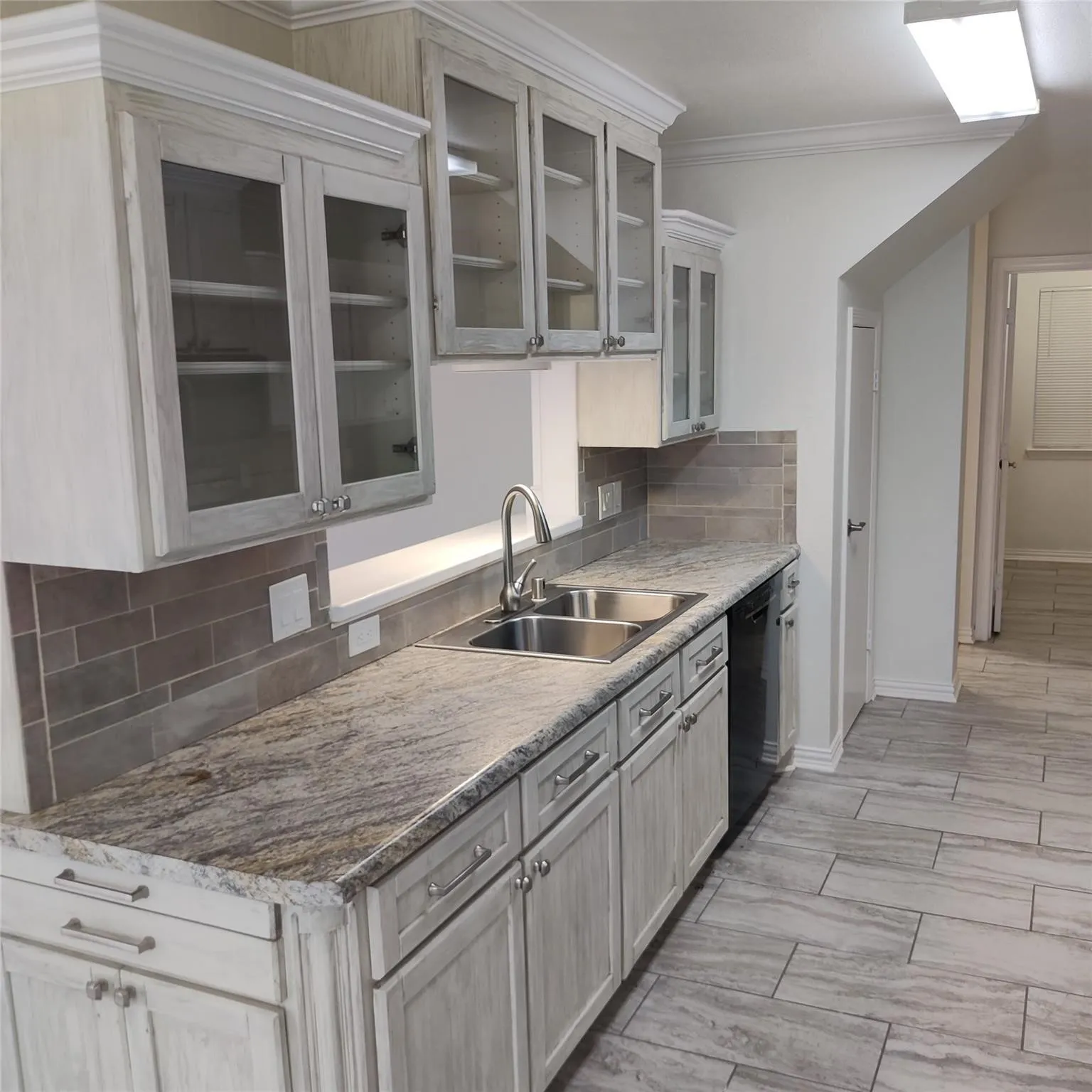 Kitchen with decorative backsplash, glass insert cabinets, crown molding, and dishwasher