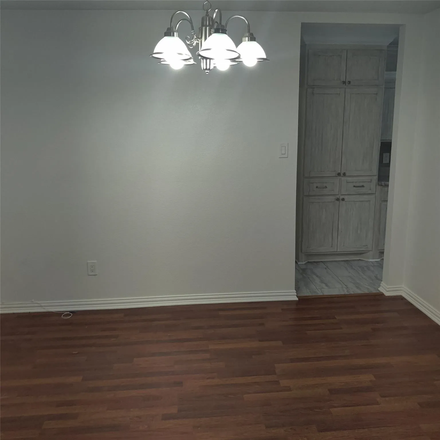 Unfurnished dining area with dark wood finished floors and a chandelier