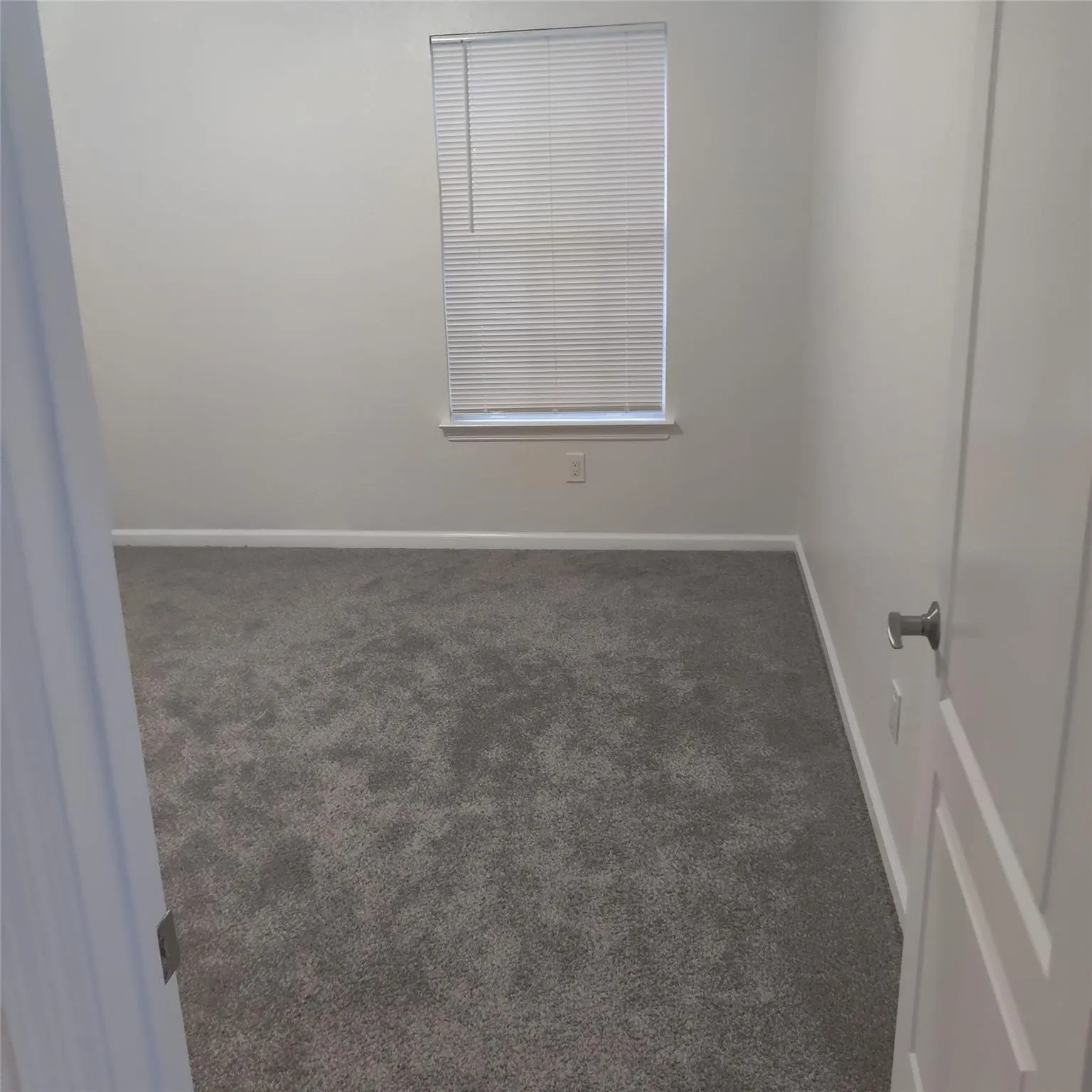Spare room with dark colored carpet and baseboards