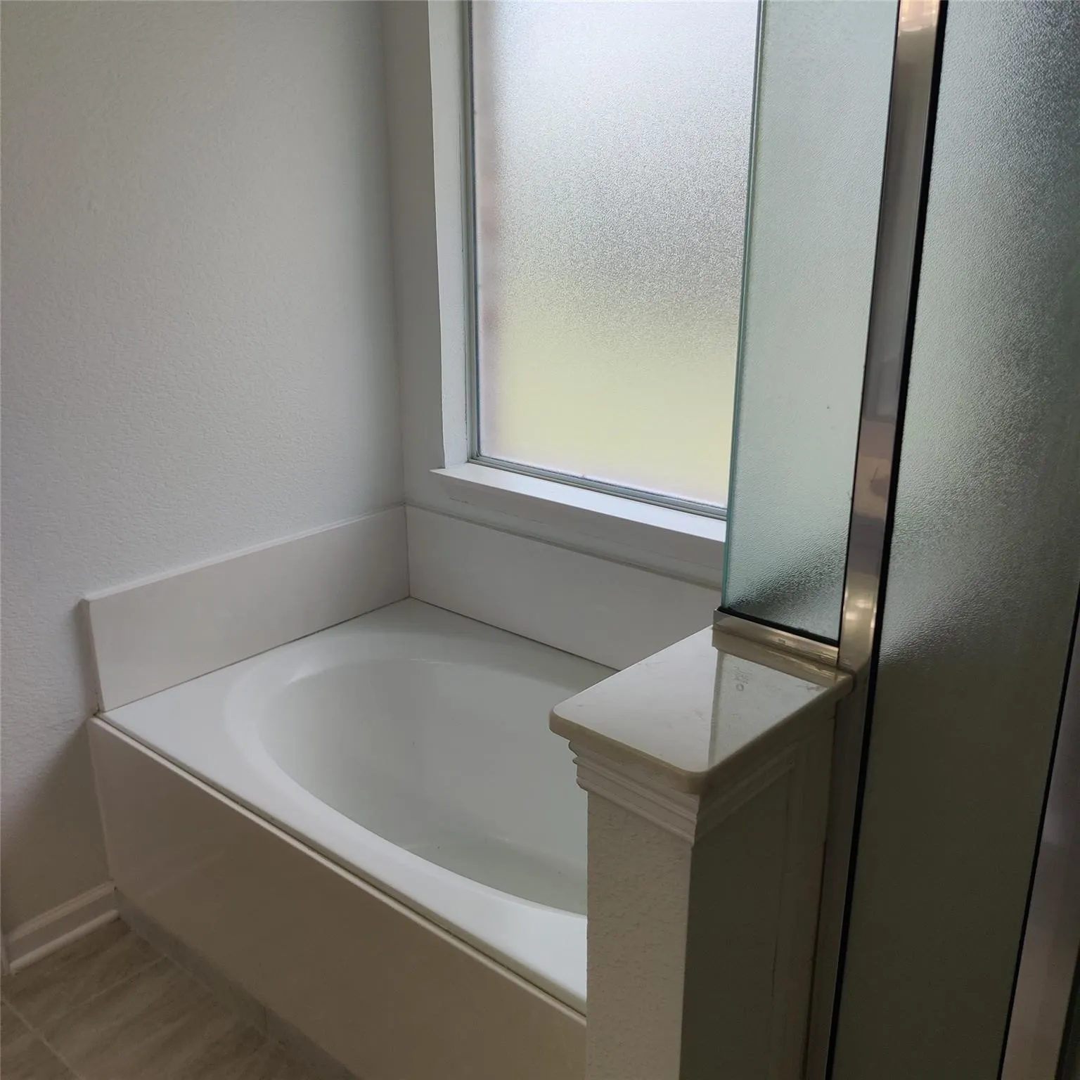 Bathroom with a garden tub and a textured wall