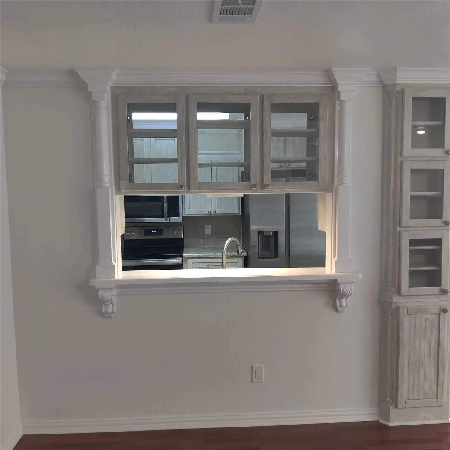 Kitchen featuring appliances with stainless steel finishes, light countertops, dark wood-type flooring, and ornamental molding