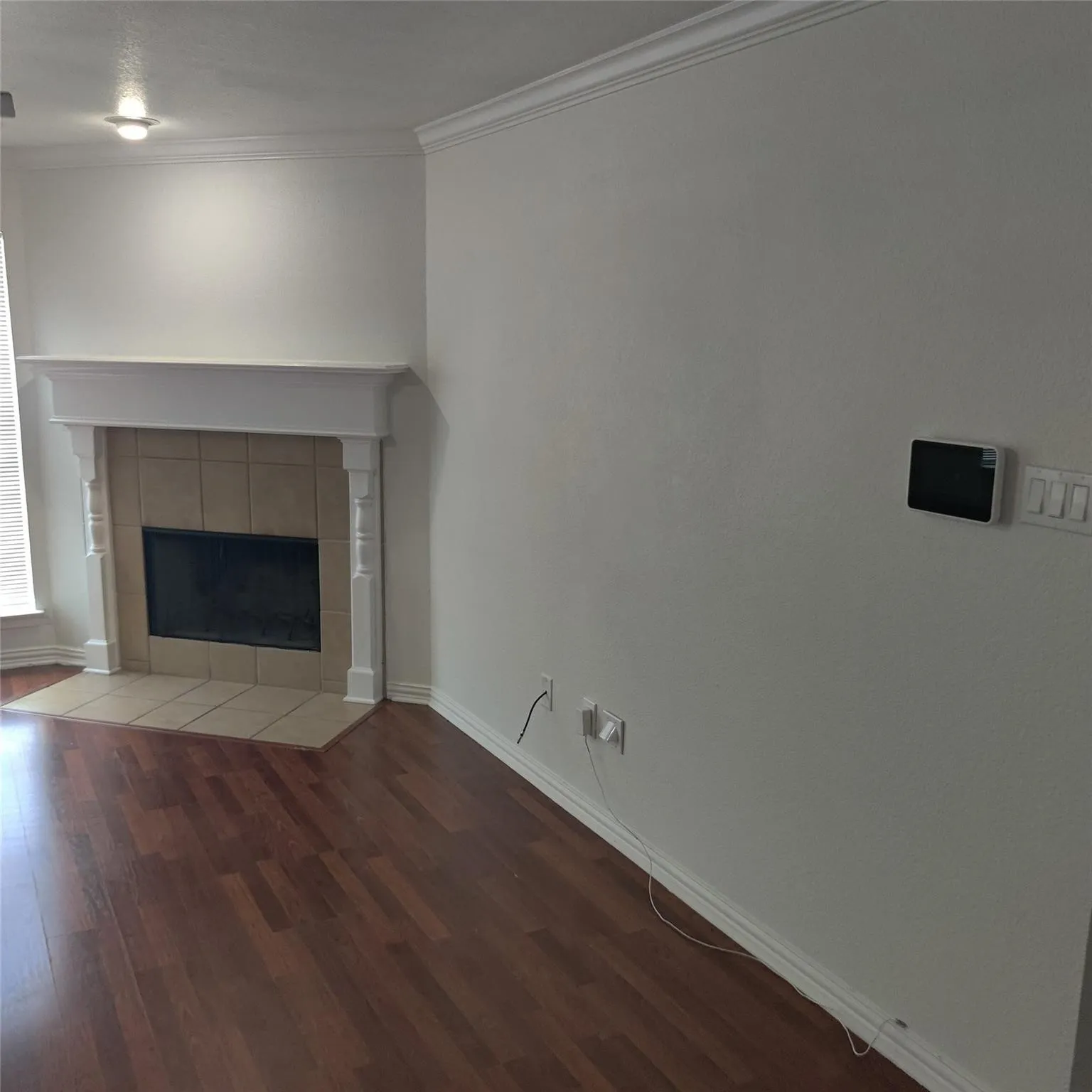 Unfurnished living room featuring wood finished floors, a fireplace, and crown molding