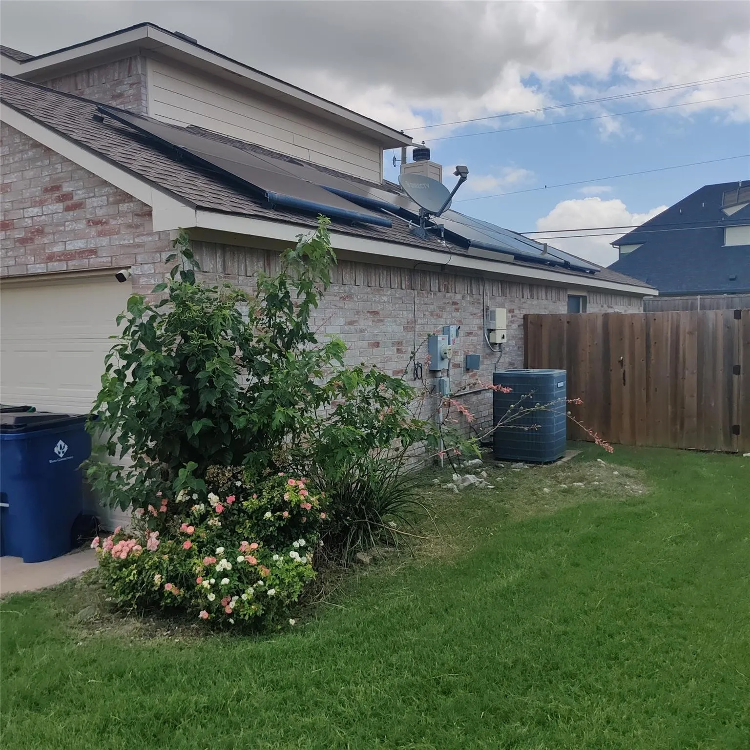 View of property exterior featuring brick siding, roof with shingles, and solar panels