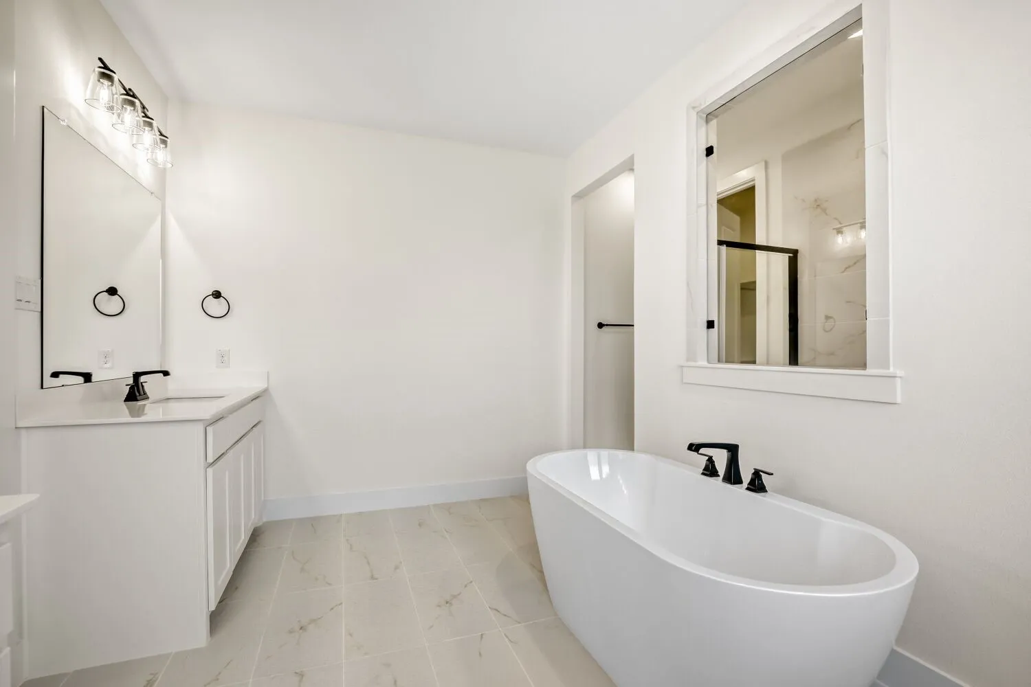 Bathroom featuring vanity, a freestanding bath, and light marble finish floors