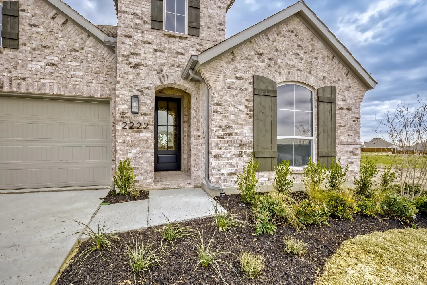 View of exterior entry featuring brick siding, a garage, and driveway