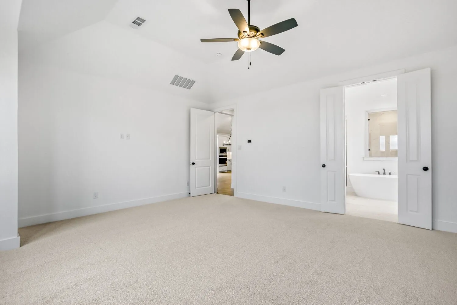 Unfurnished bedroom with light carpet, a ceiling fan, vaulted ceiling, and ensuite bathroom