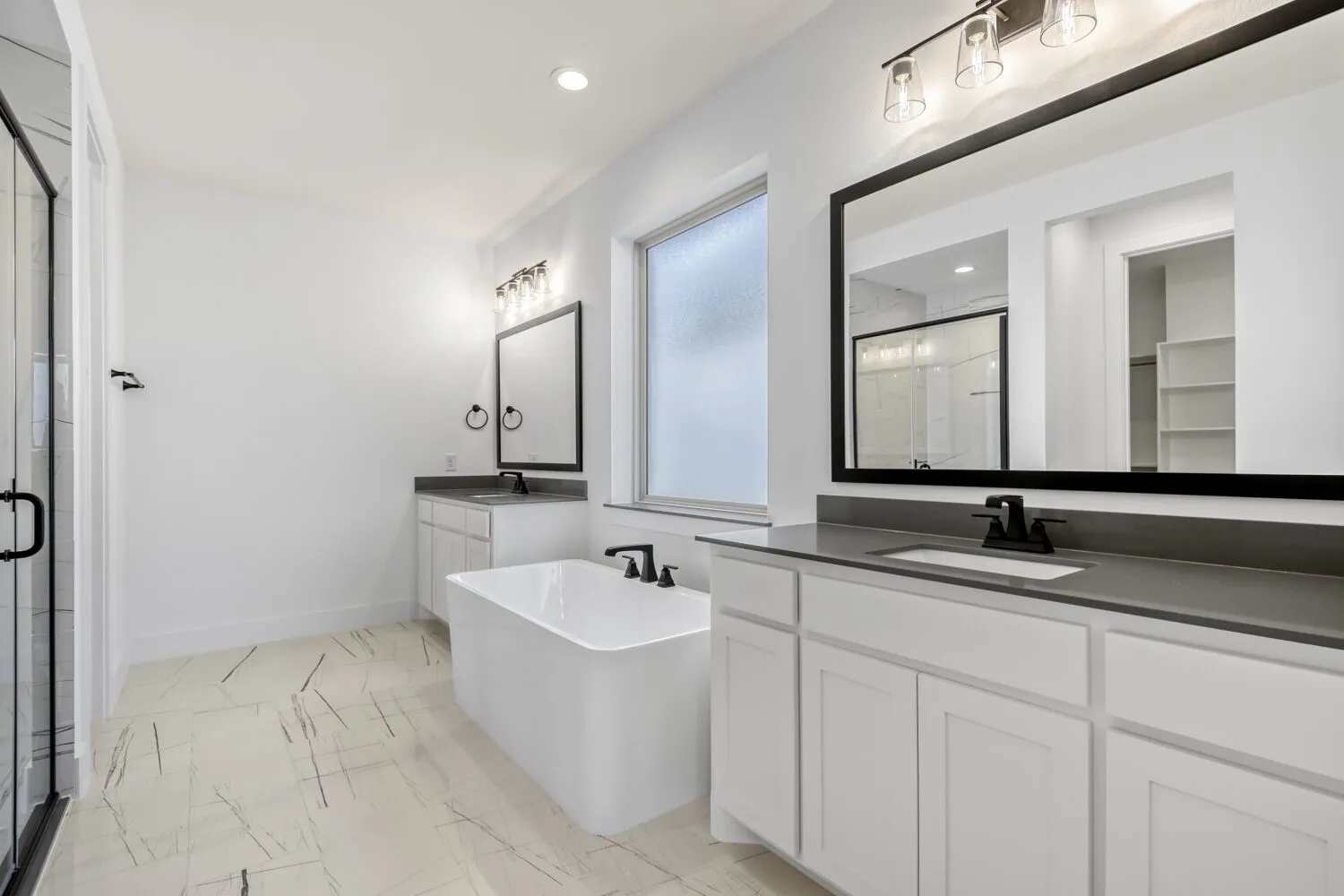 Bathroom featuring a soaking tub, two vanities, a marble finish shower, recessed lighting, and light marble finish flooring