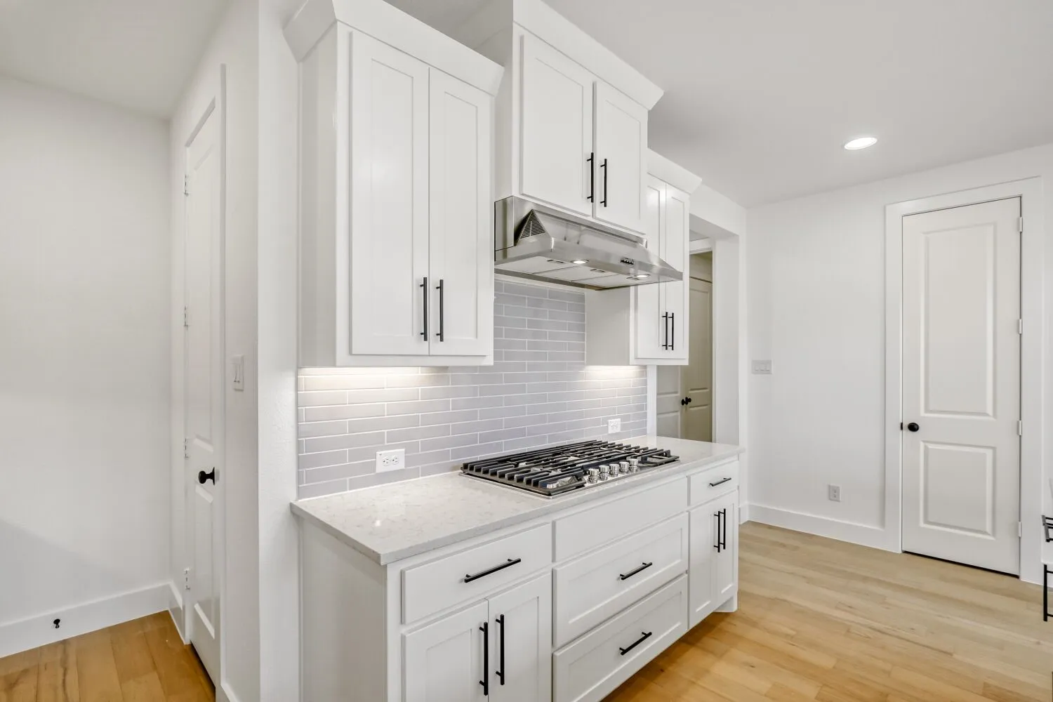 Kitchen with white cabinets, light stone countertops, light wood-type flooring, recessed lighting, and stainless steel gas​​‌​​​​‌​​‌‌​‌‌​​​‌‌​‌​‌​‌​​​‌​​ stovetop