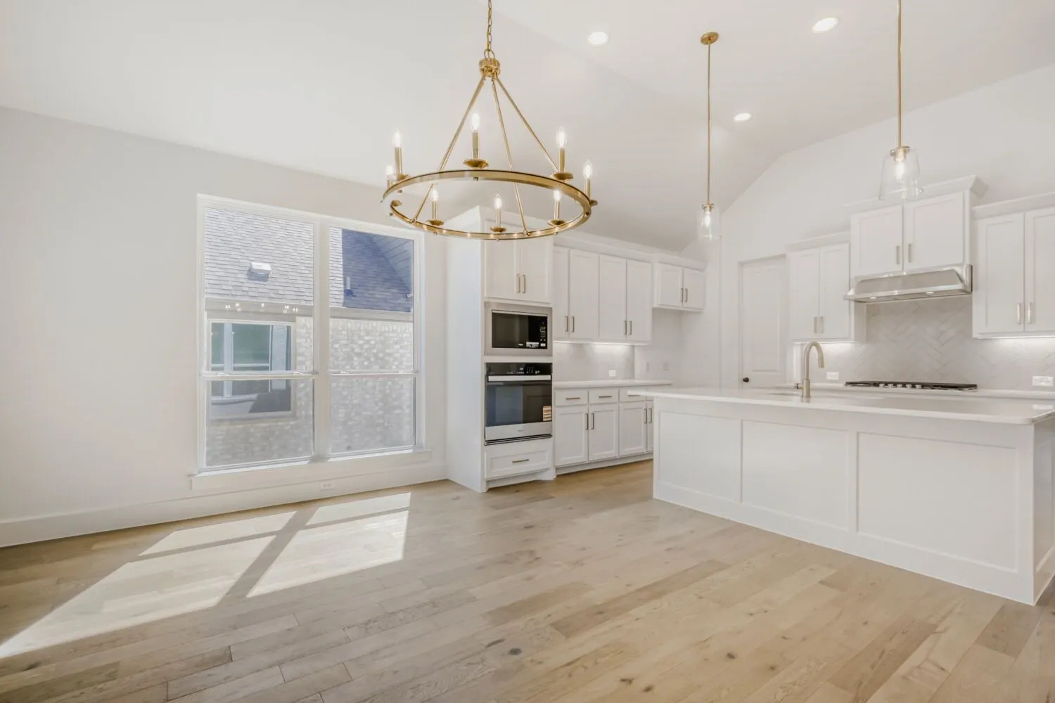 Kitchen with white cabinets, a chandelier, oven, light wood finished floors, and lofted ceiling