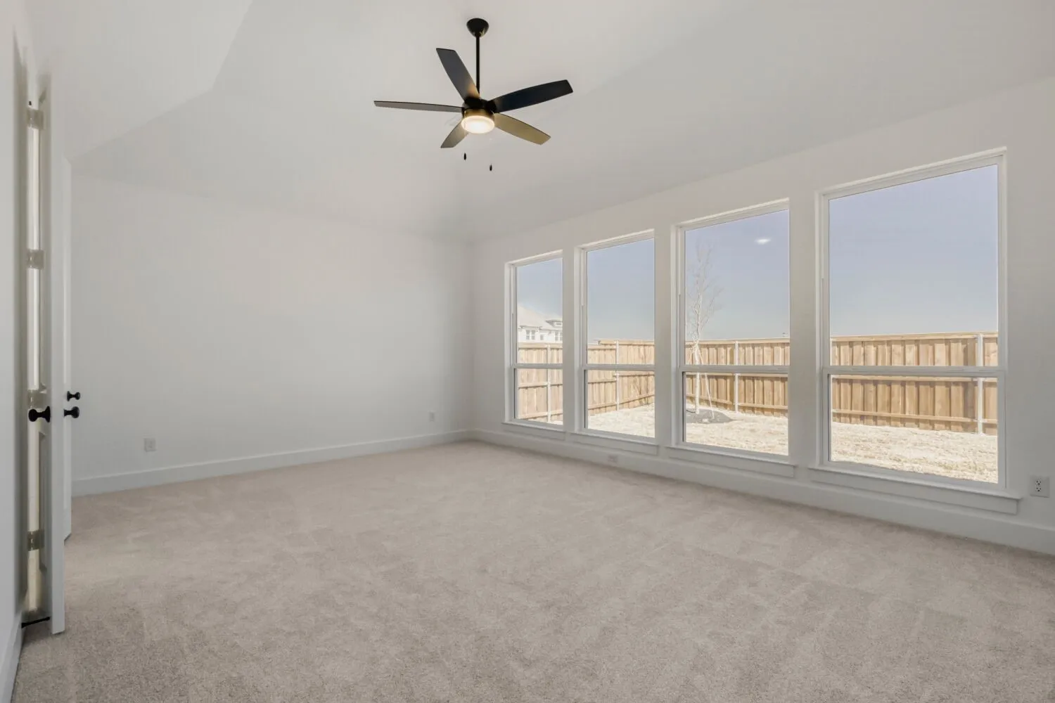 Unfurnished room with a ceiling fan, light carpet, and vaulted ceiling