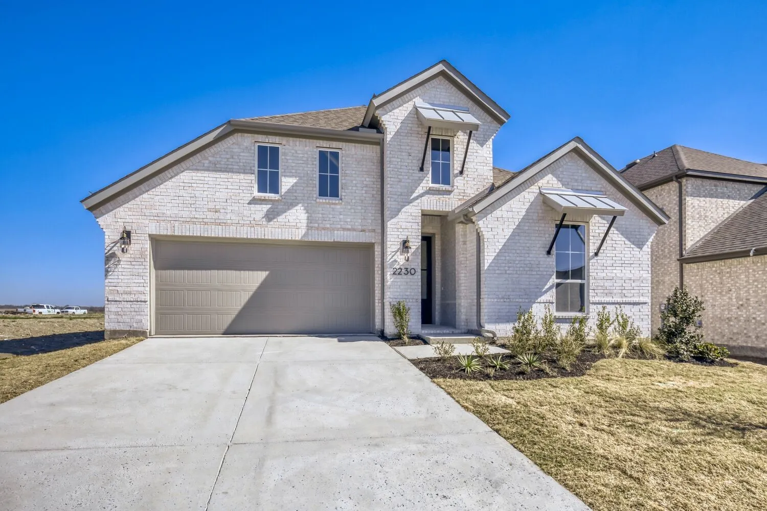 View of front of home featuring concrete driveway, brick siding, a standing seam roof, and a front lawn
