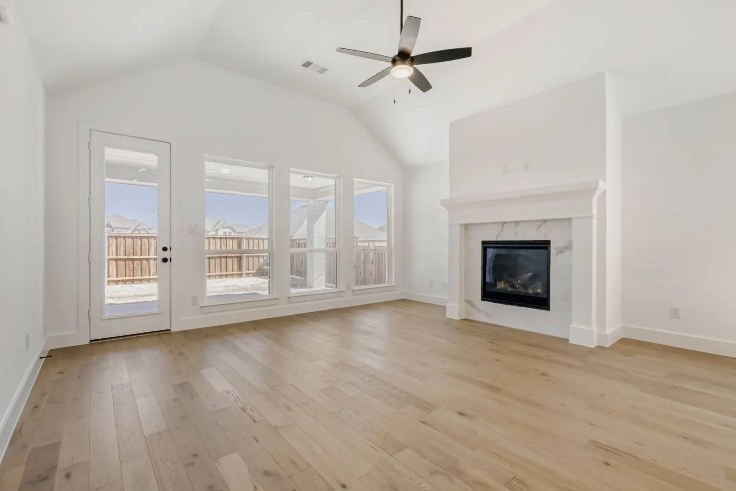 Unfurnished living room with ceiling fan, light wood-style floors, a high end fireplace, and a high ceiling