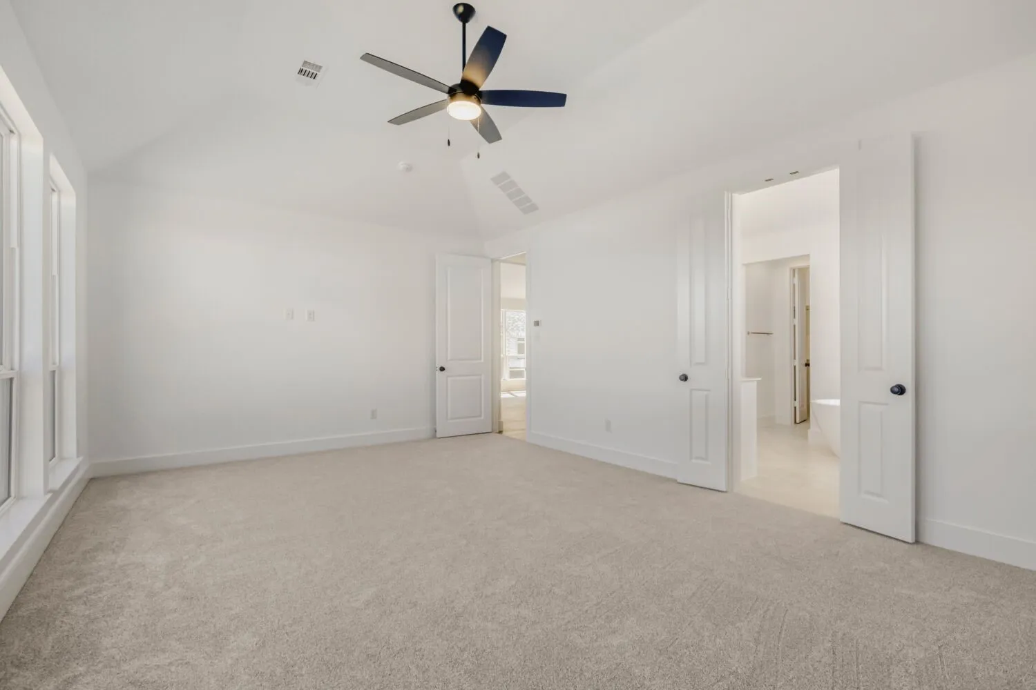 Unfurnished bedroom featuring light carpet, a ceiling fan, and vaulted ceiling