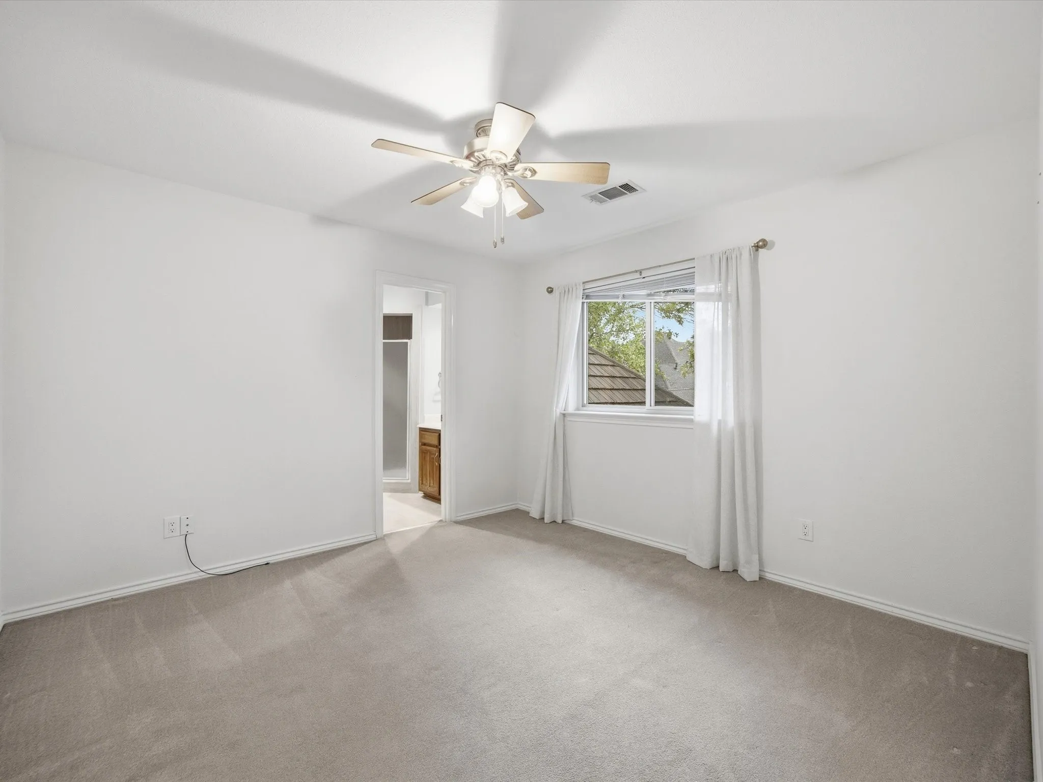 Bedoom with light colored carpet and ceiling fan