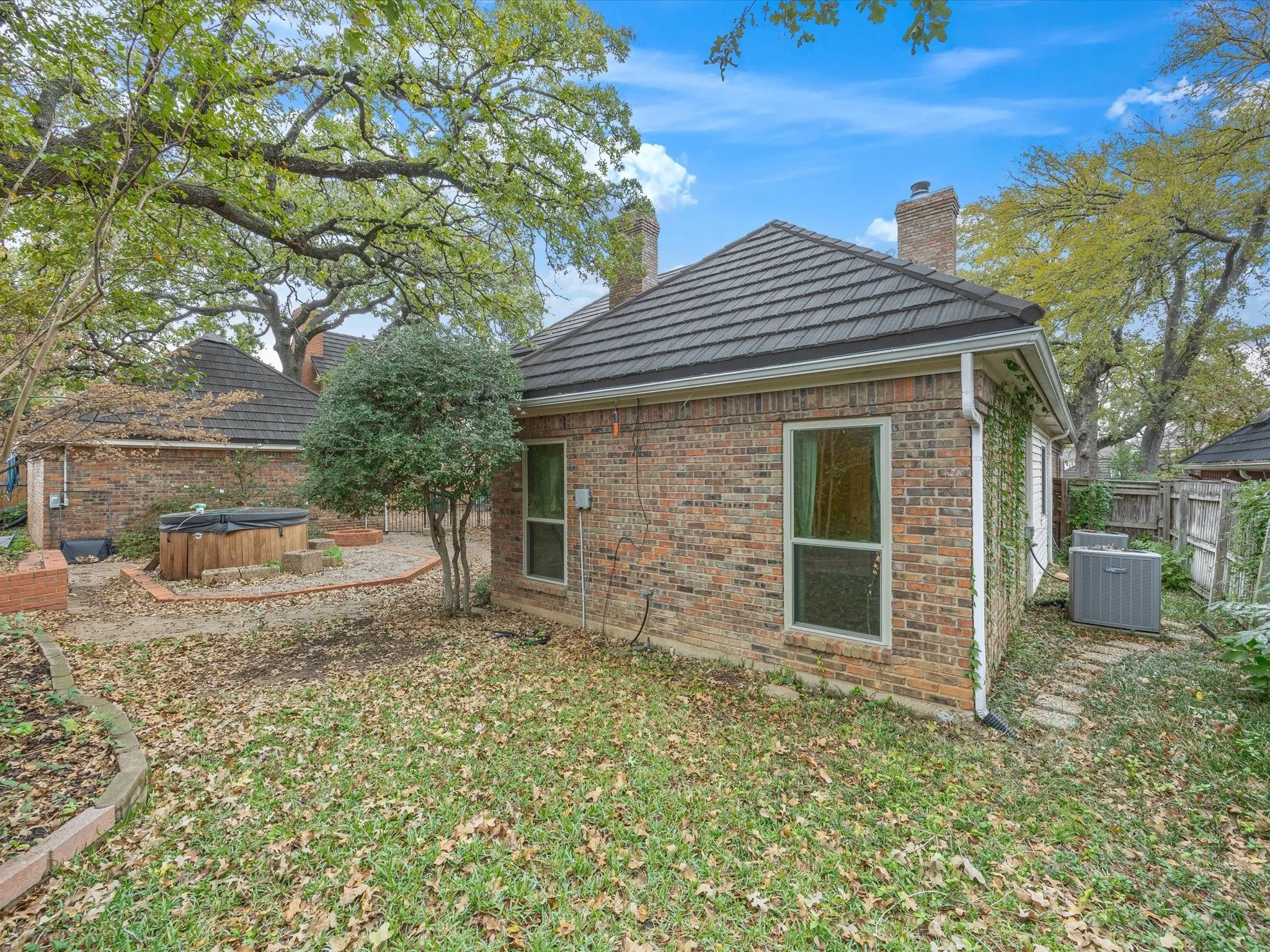 Rear view of property featuring a hot tub, a chimney, and brick siding