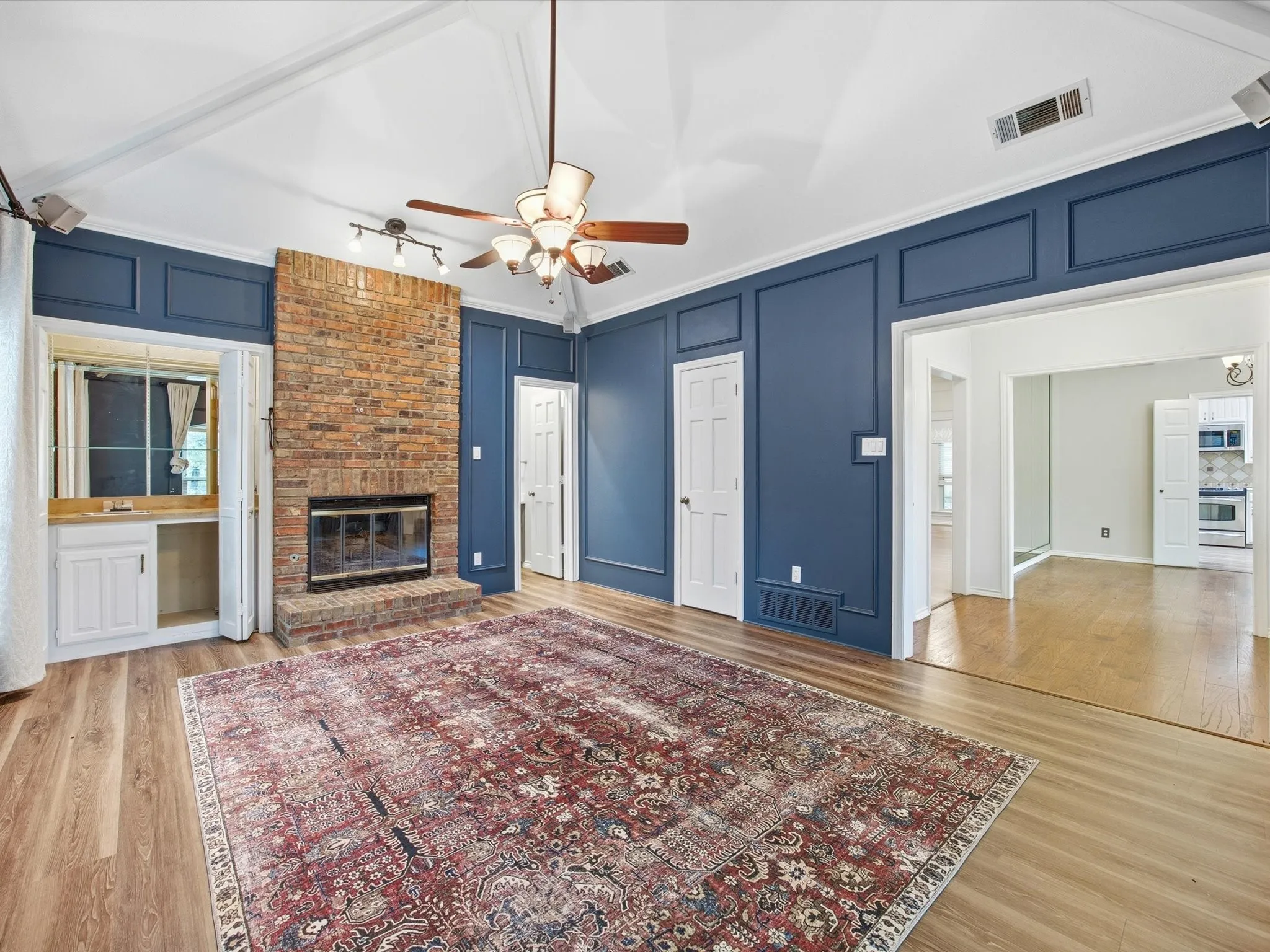 Unfurnished living room featuring a decorative wall, light wood-style flooring, a fireplace, and ceiling fan