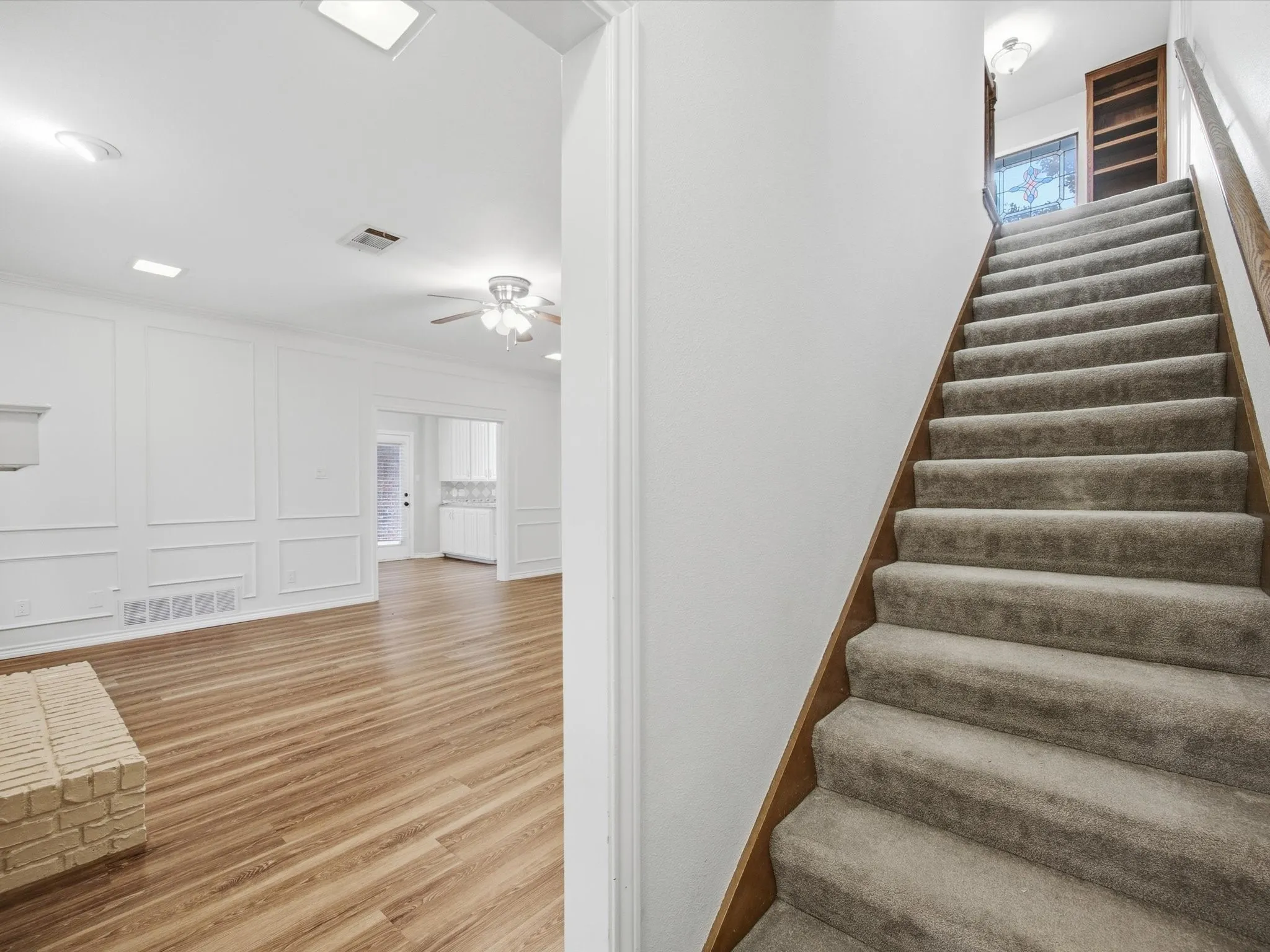 Stairs with a decorative wall, wood finished floors, and ceiling fan