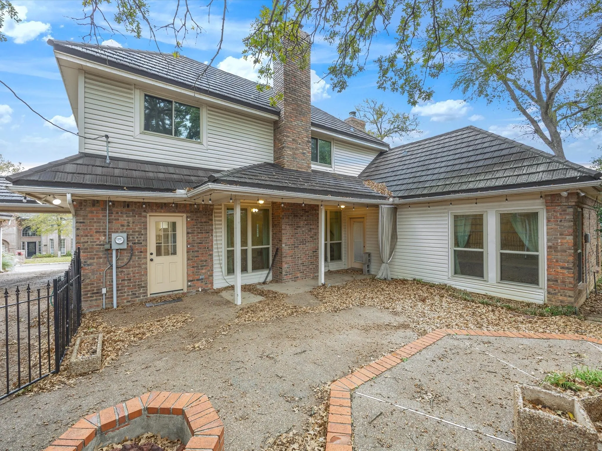 Rear view of property featuring a fire pit, a chimney, brick siding, and a patio