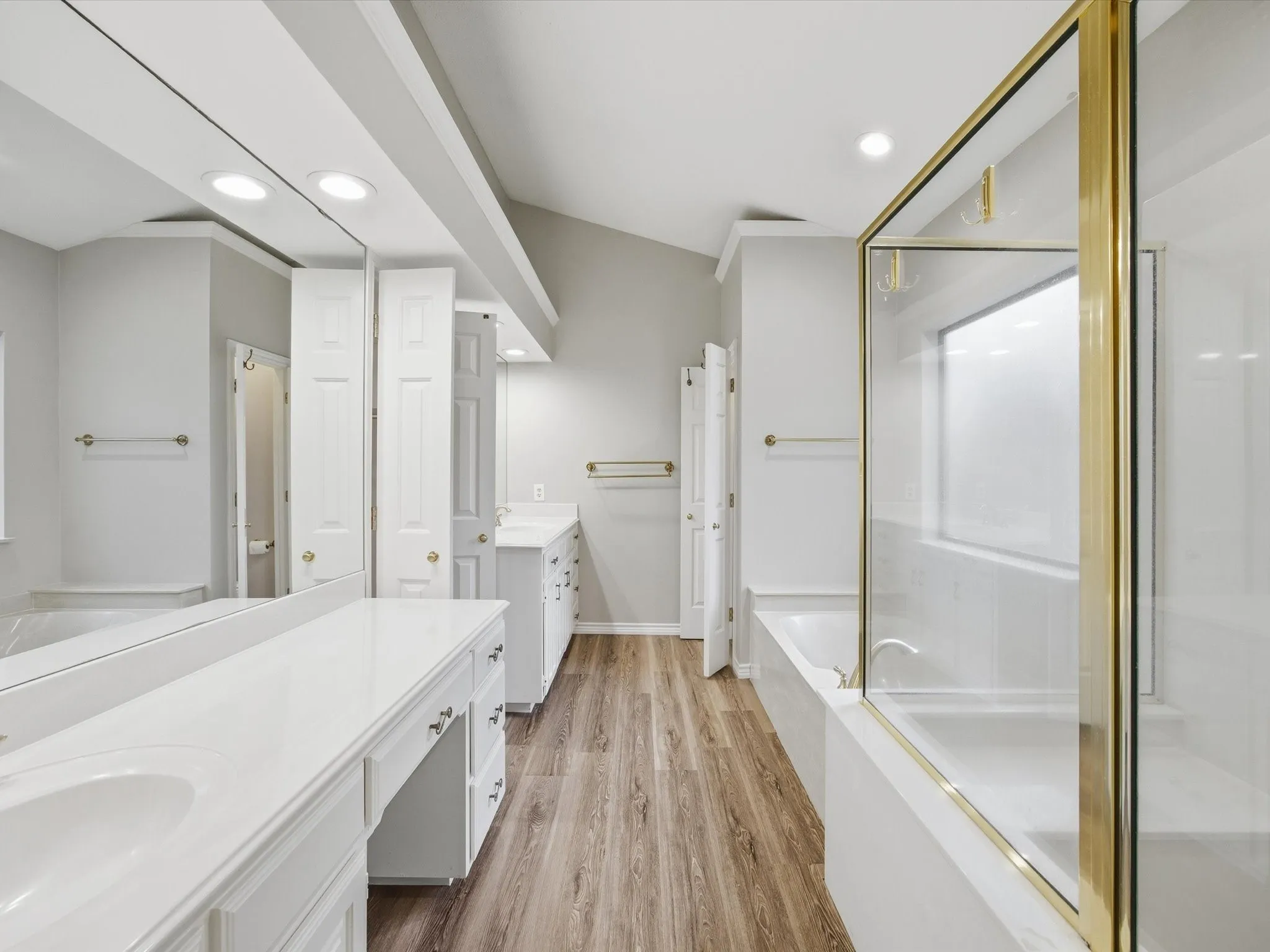 Primary Bathroom with a bath, light wood-type flooring, two vanities, a stall shower, and recessed lighting
