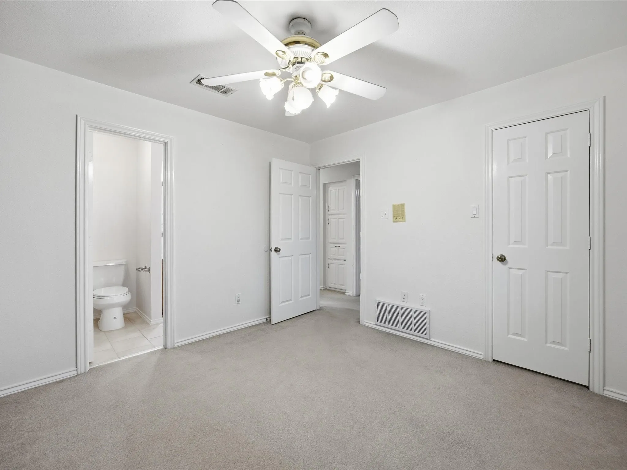 Unfurnished bedroom featuring light carpet, a ceiling fan, and connected bathroom