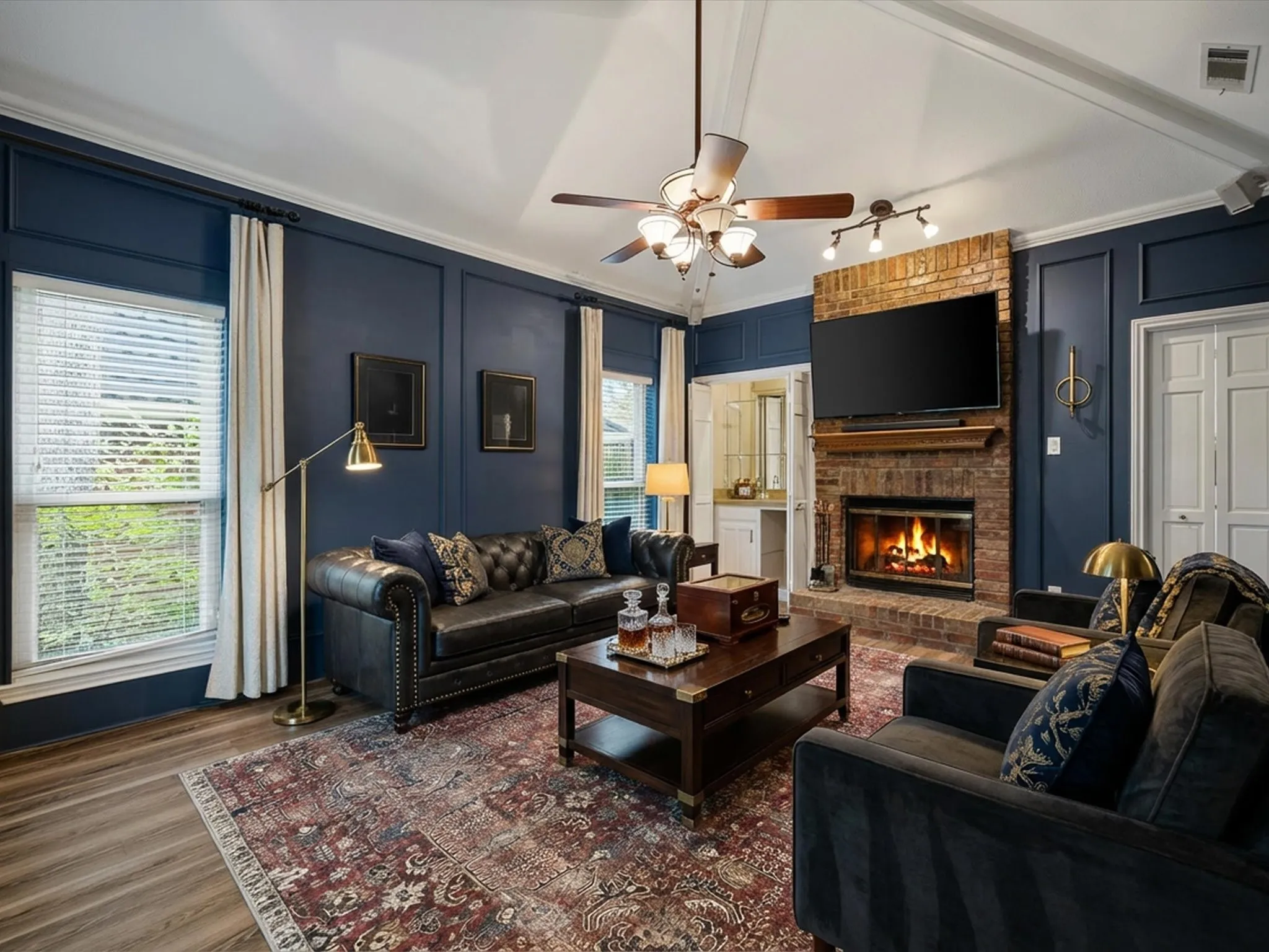 Living area with a decorative wall, a fireplace, wood finished floors, and ceiling fan