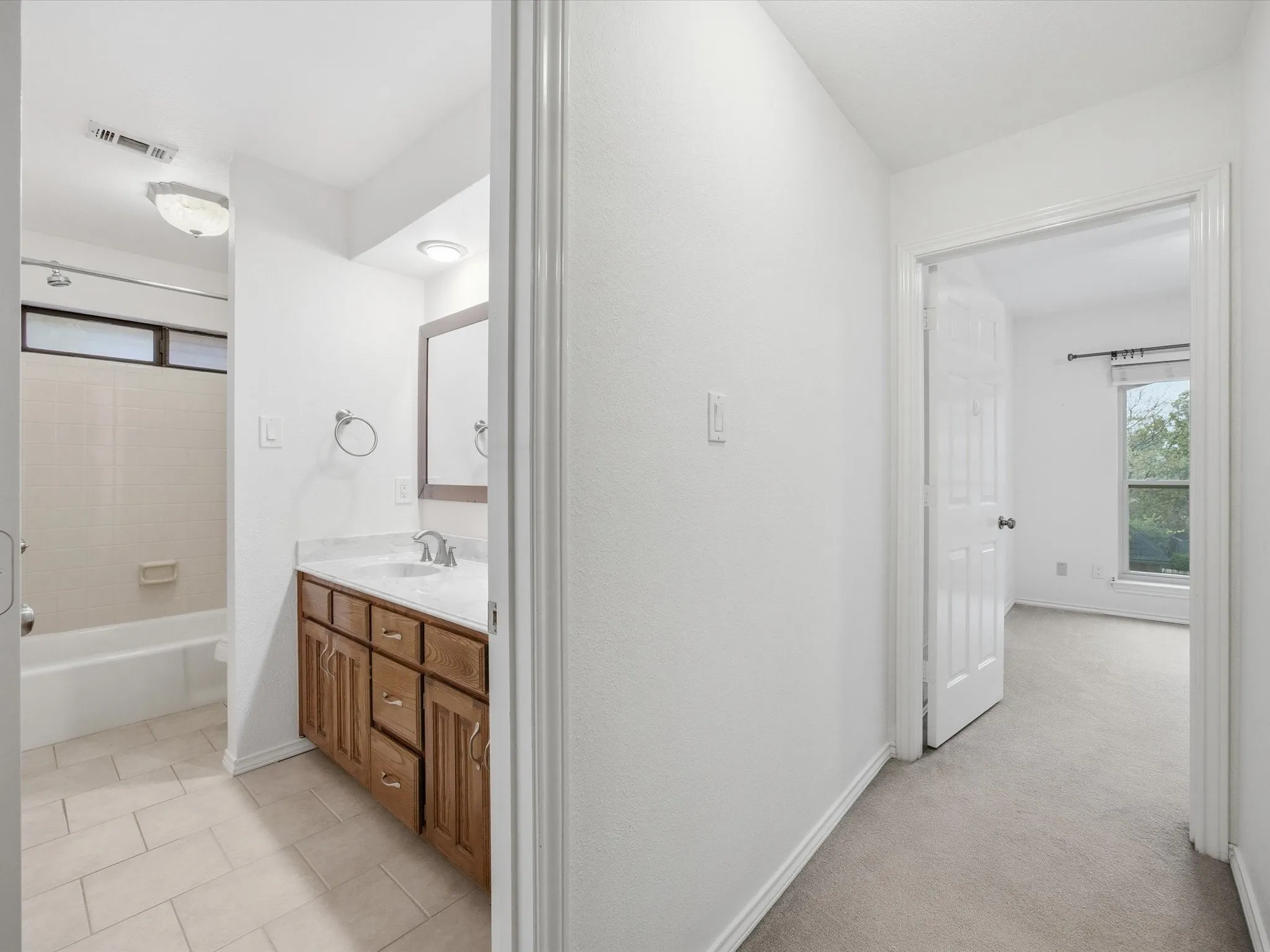 Bathroom with plenty of natural light, vanity, shower / tub combination, and light colored carpet