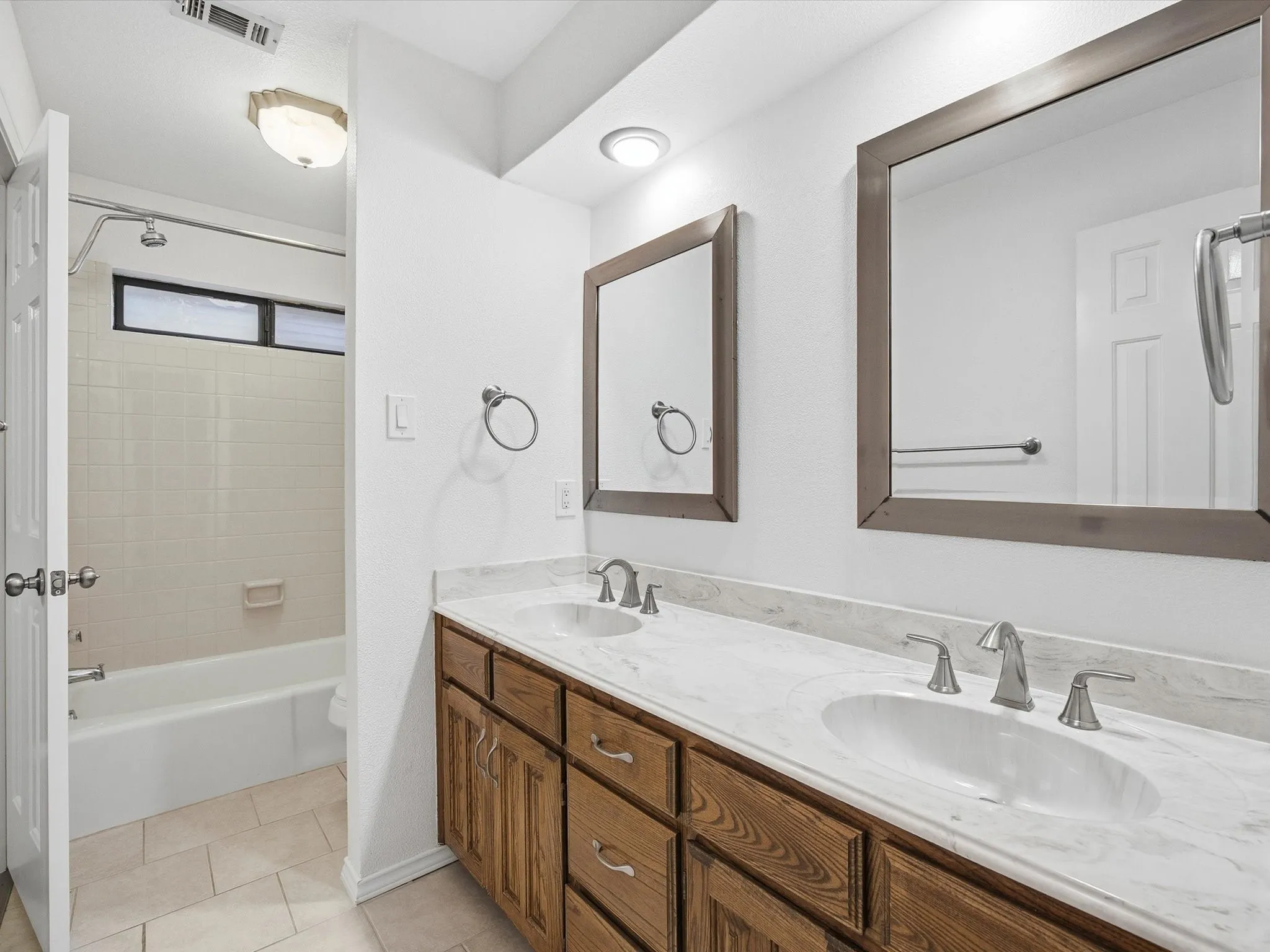 Full bath with double vanity, shower / tub combination, and light tile patterned floors