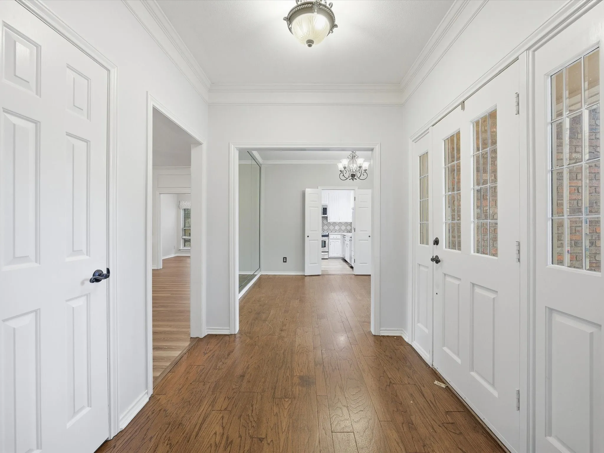 Hallway featuring ornamental molding, a chandelier, and dark wood-style floors
