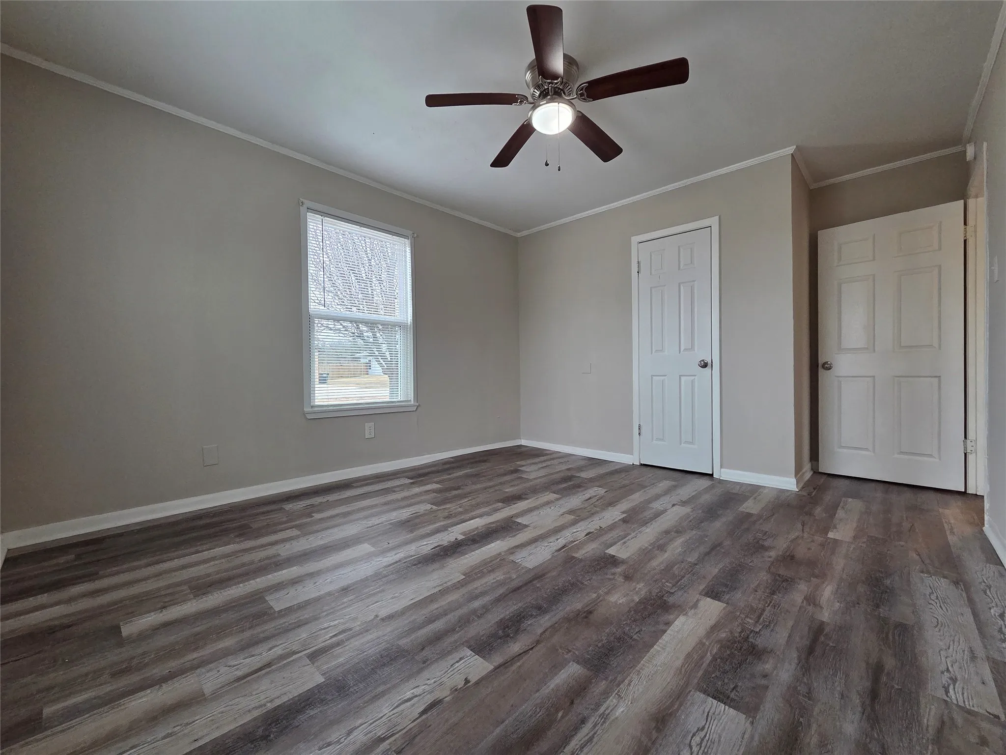 Unfurnished bedroom featuring crown molding, a ceiling fan, dark wood-style floors, and a closet