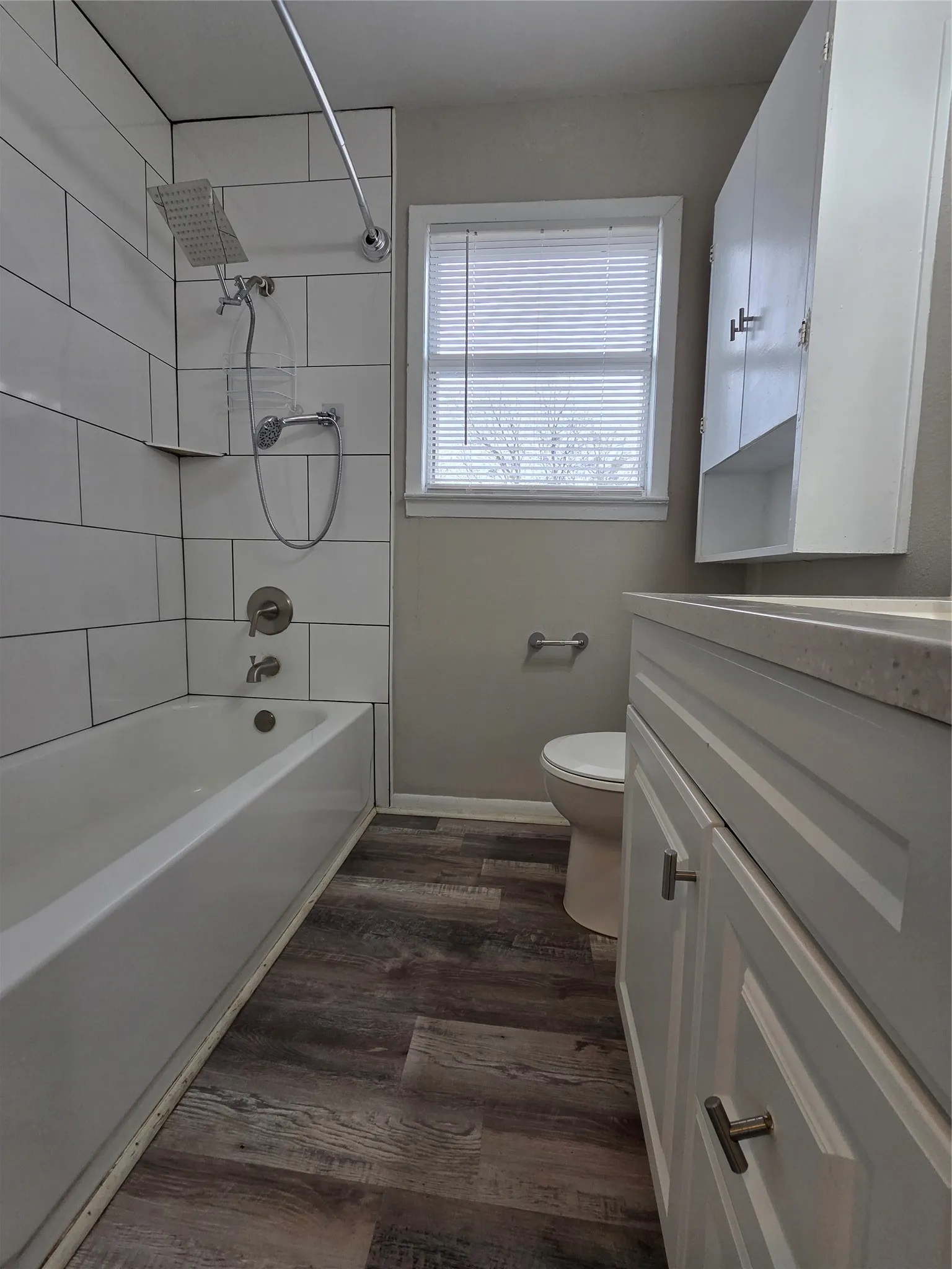 Bathroom featuring vanity, washtub / shower combination, and dark wood-type flooring