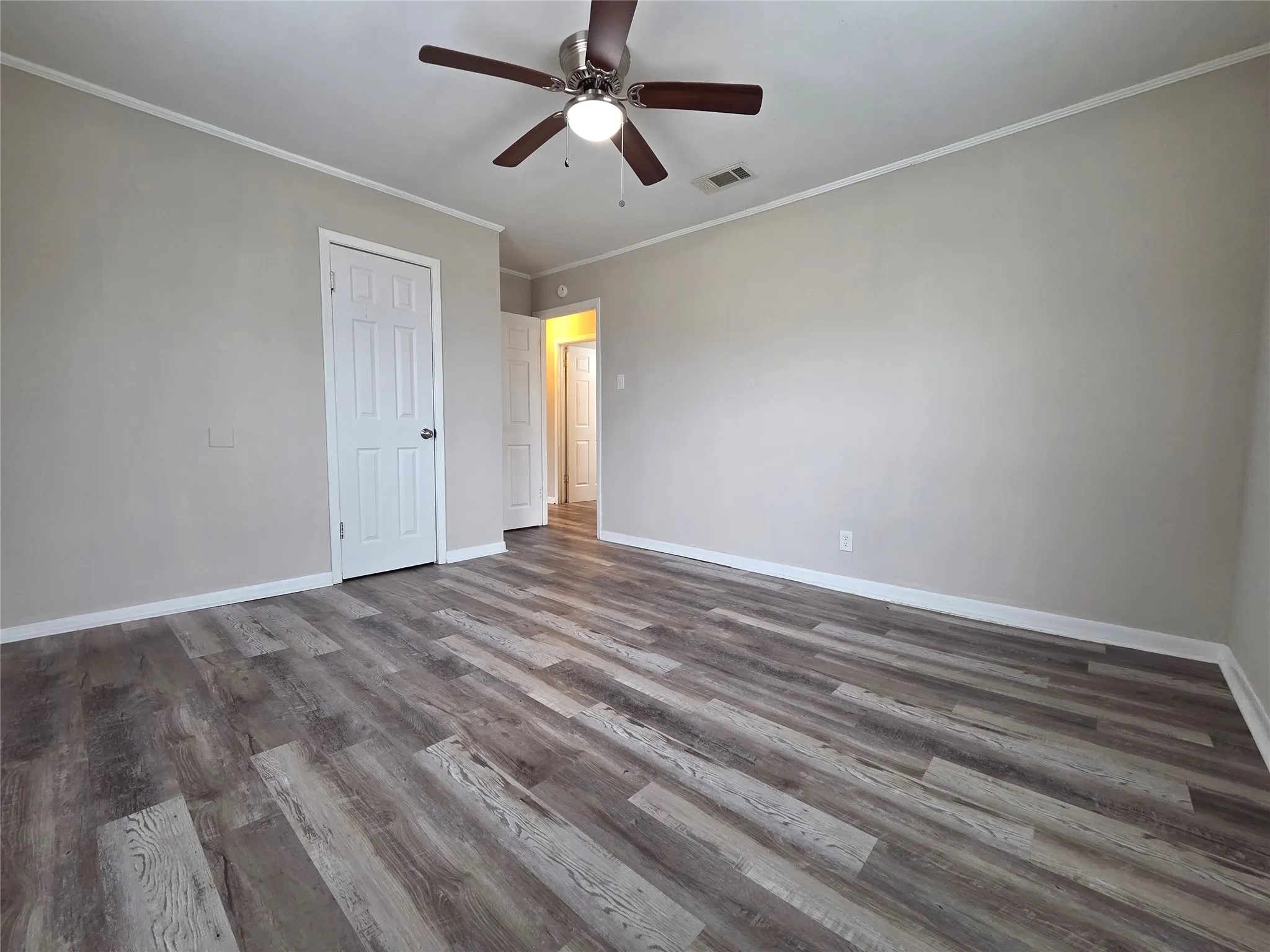Unfurnished bedroom featuring ornamental molding, a ceiling fan, and wood finished floors