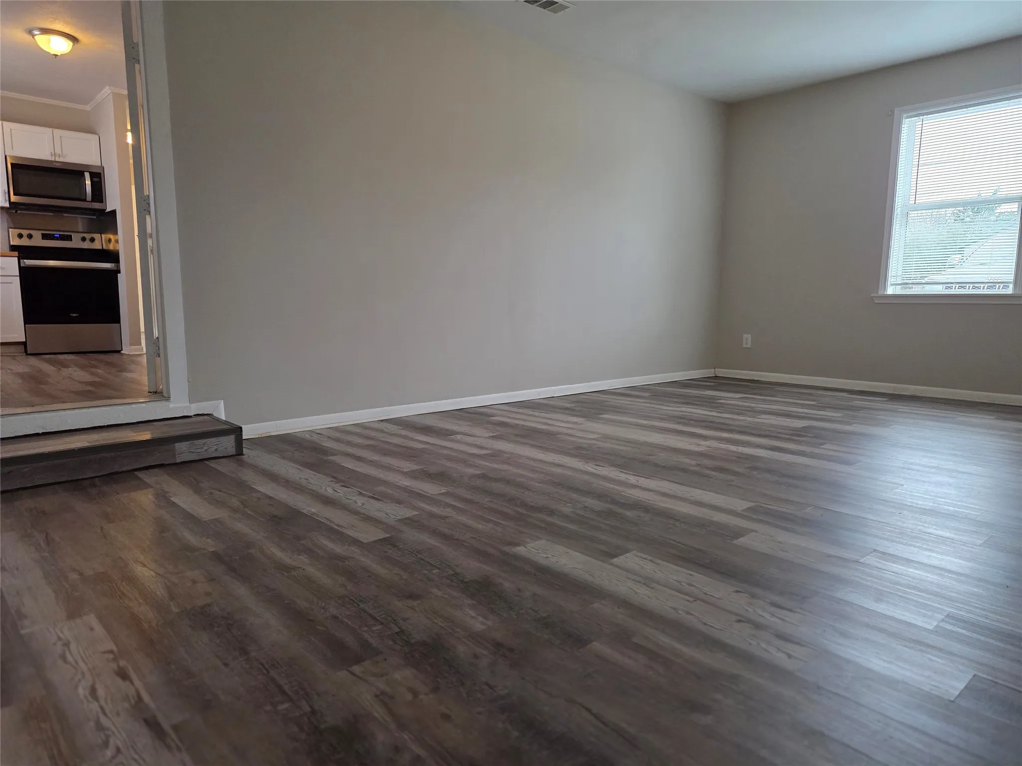 Spare room with dark wood-type flooring and baseboards
