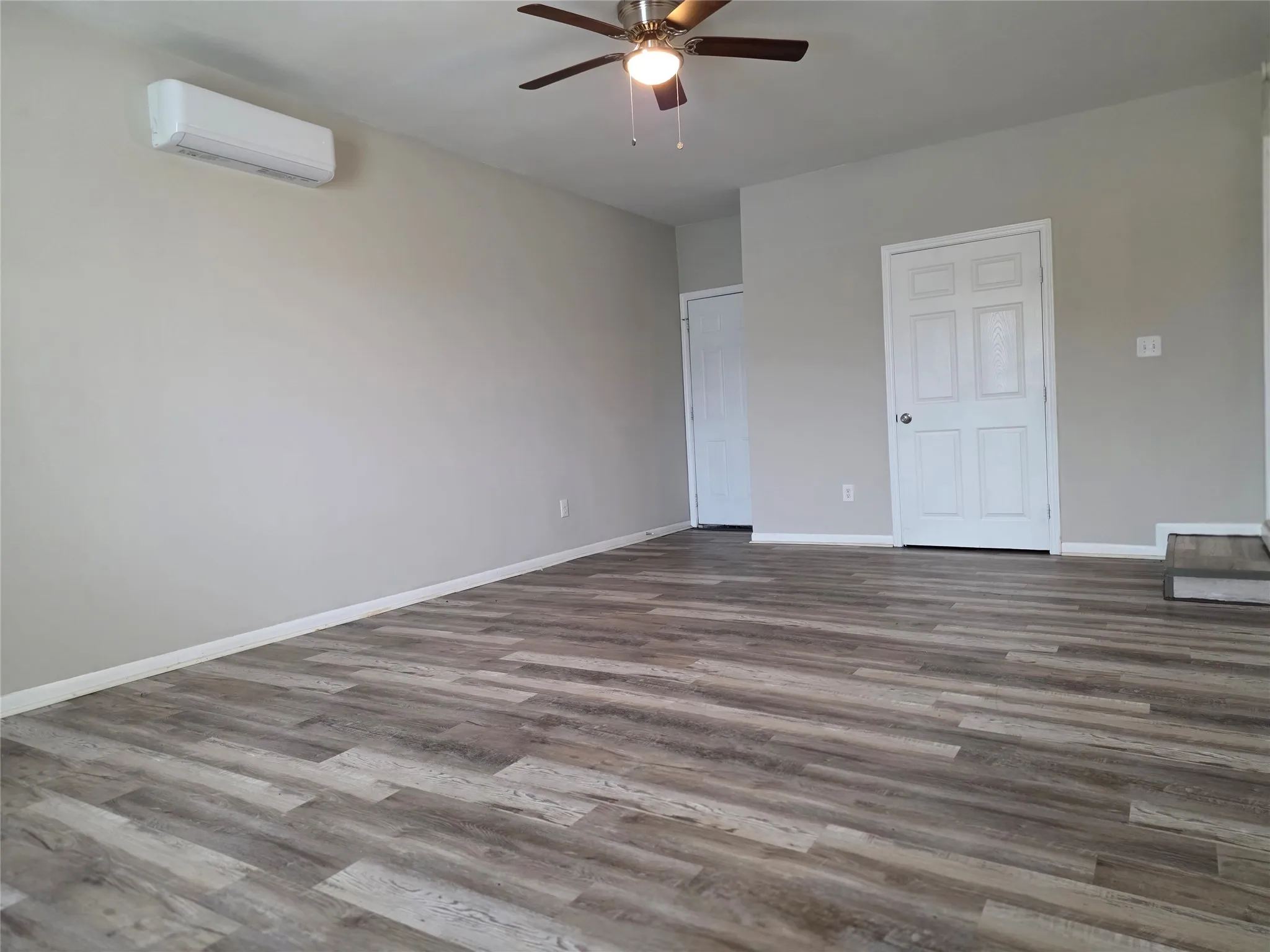 Unfurnished bedroom featuring a ceiling fan, wood finished floors, and a wall mounted mini split