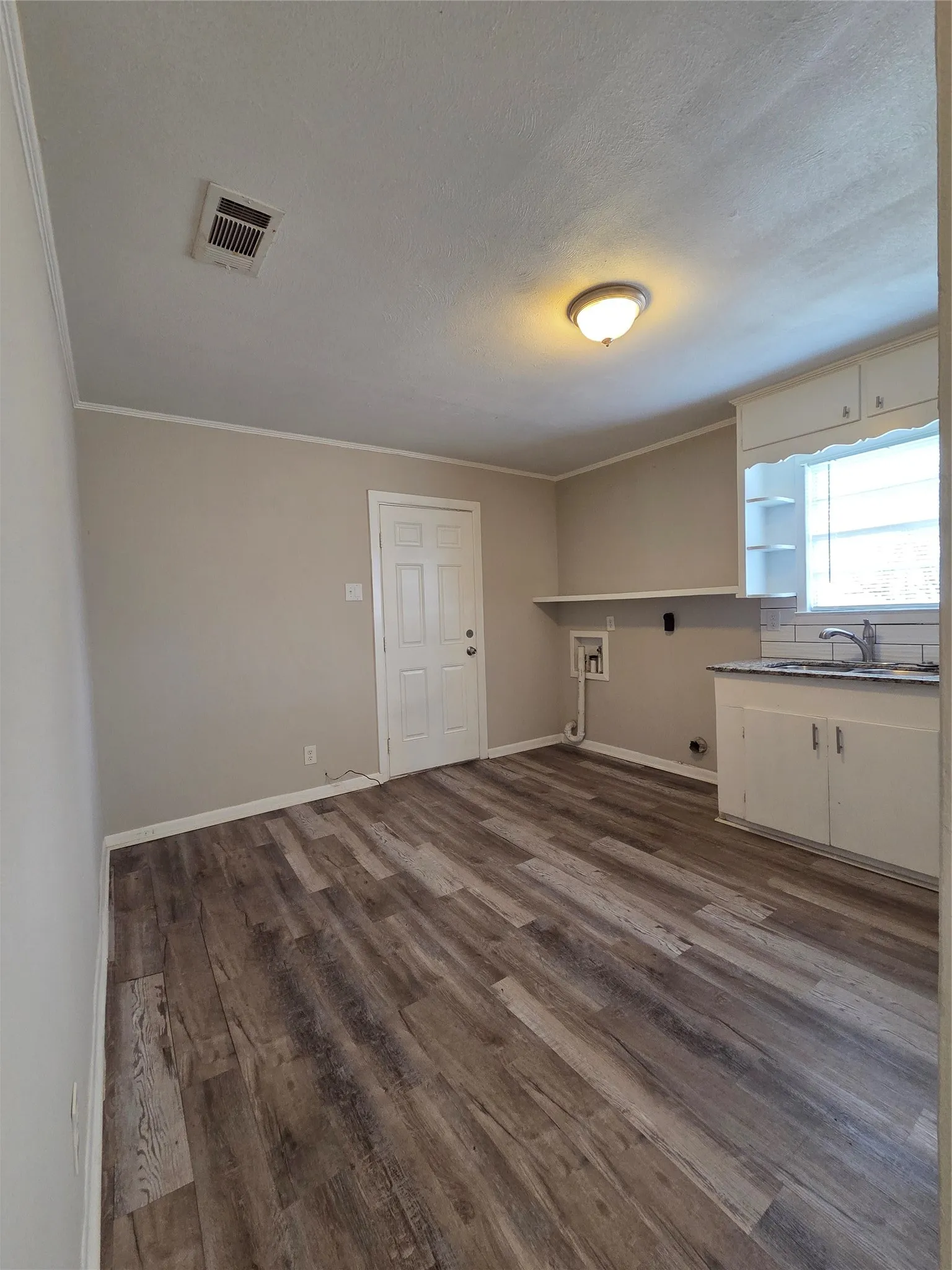 Laundry room featuring dark wood-type flooring, hookup for a washing machine, ornamental molding, and hookup for an electric dryer