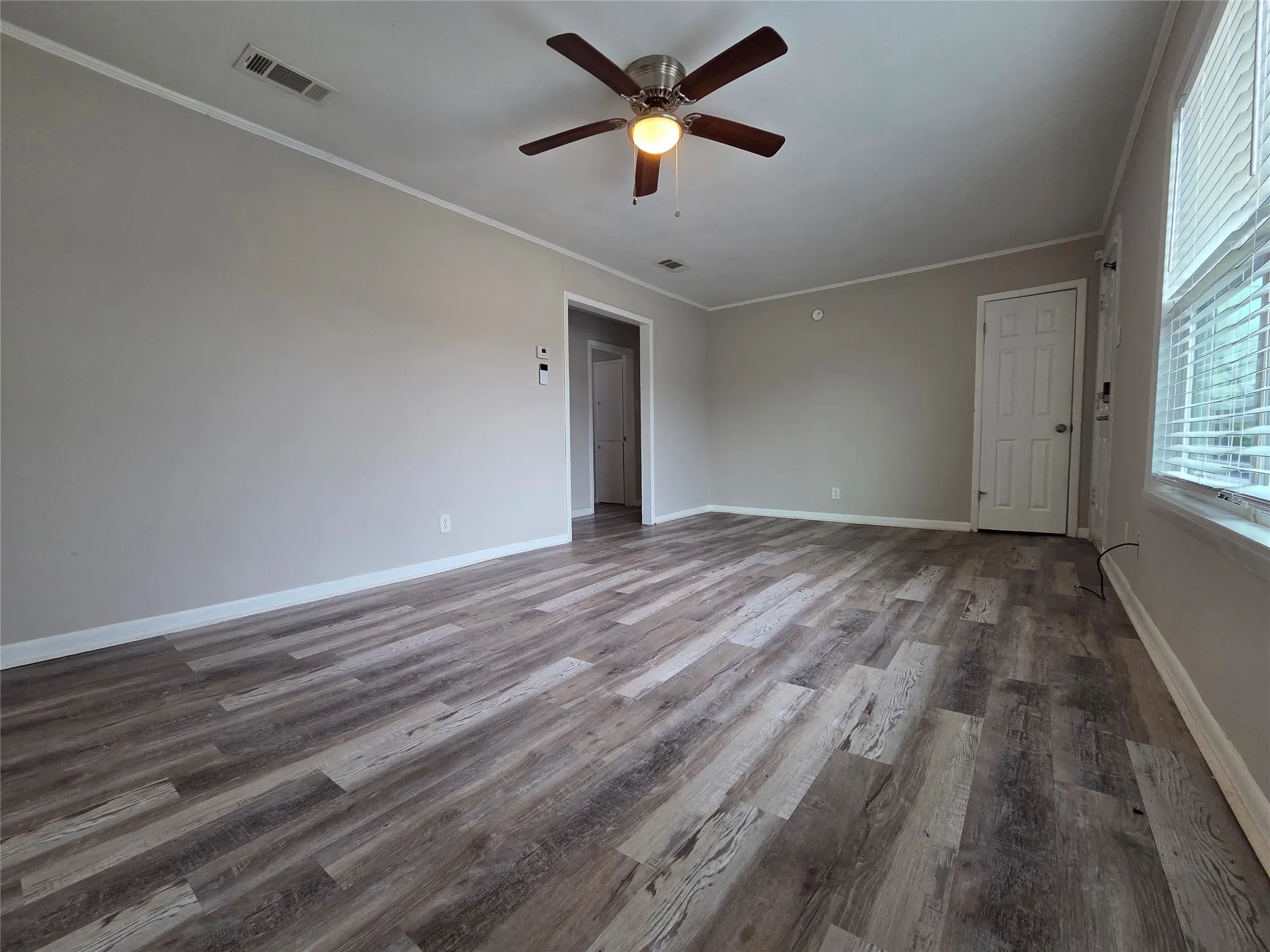 Empty room featuring crown molding, wood finished floors, and a ceiling fan