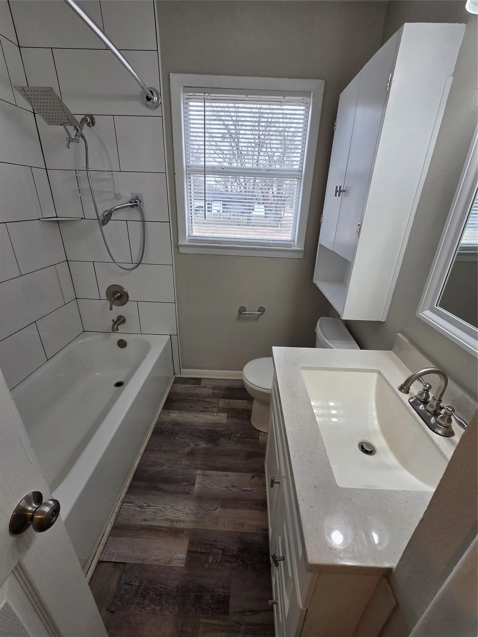Bathroom with dark wood-type flooring, bathtub / shower combination, and vanity