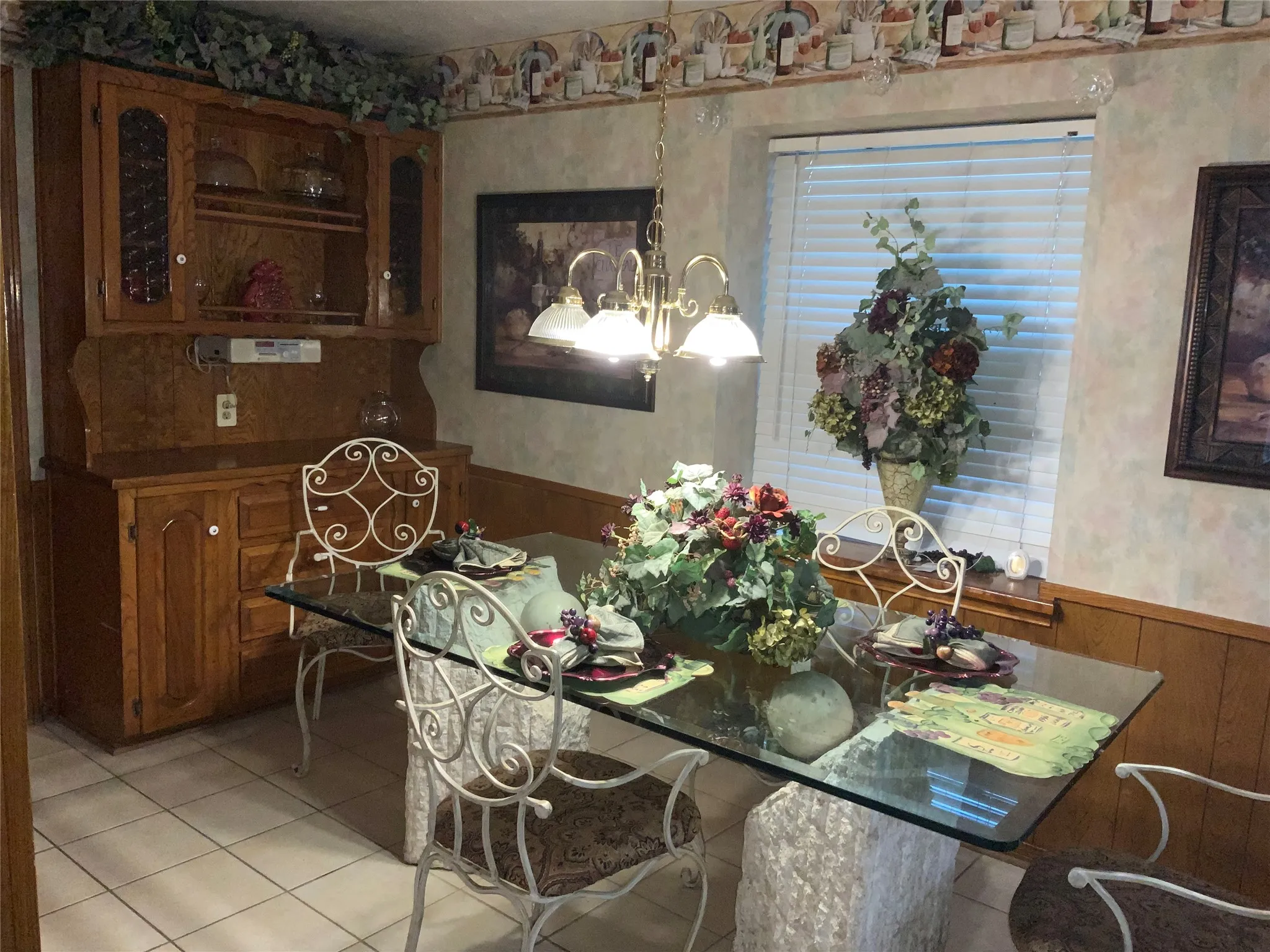 Elegant dining area featuring a glass-top table, ornate metal chairs, and tile flooring