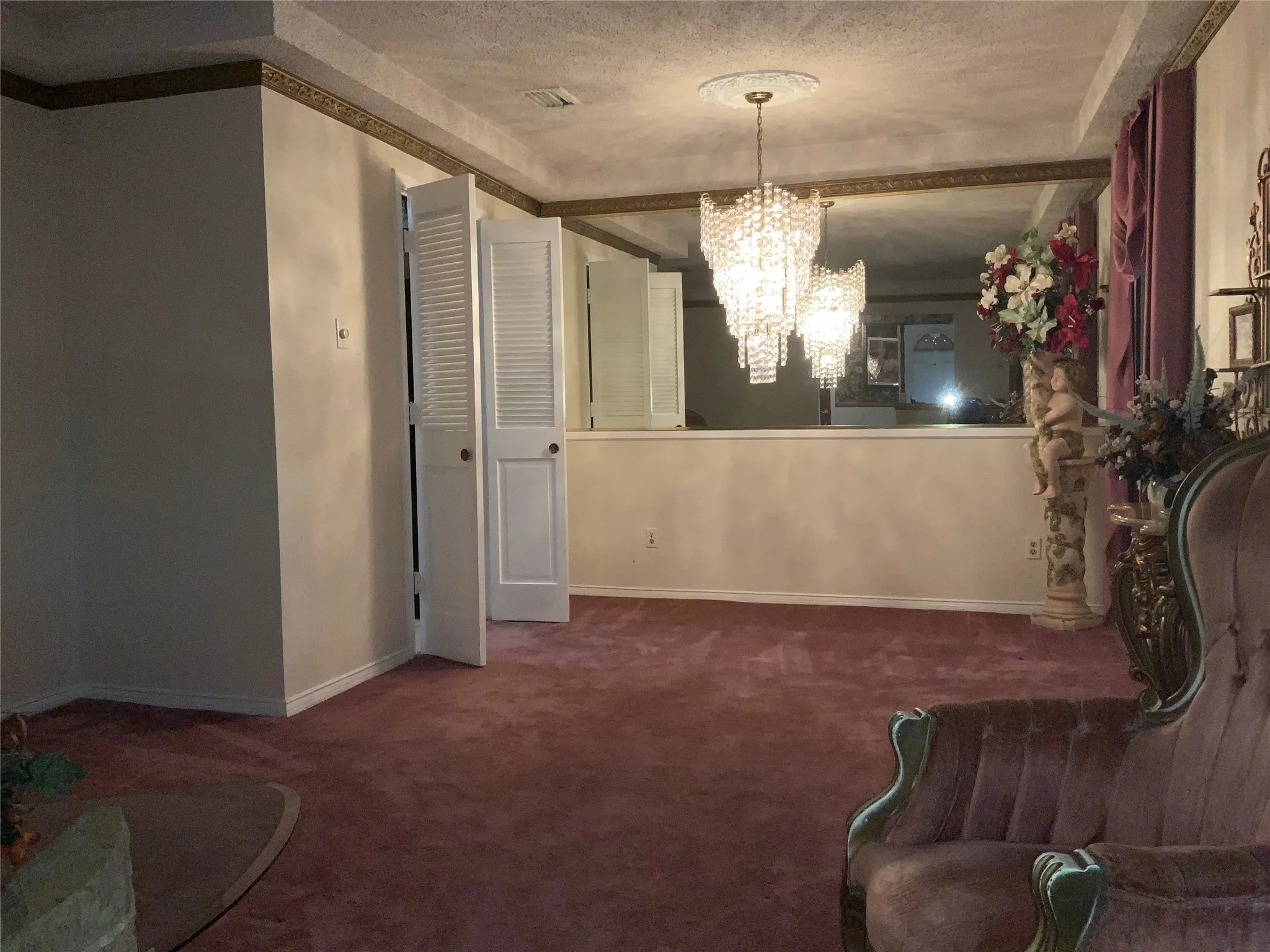 Recessed ceiling with decorative molding, chandelier lighting, bi-fold louvered doors, and wall-mounted mirror panels