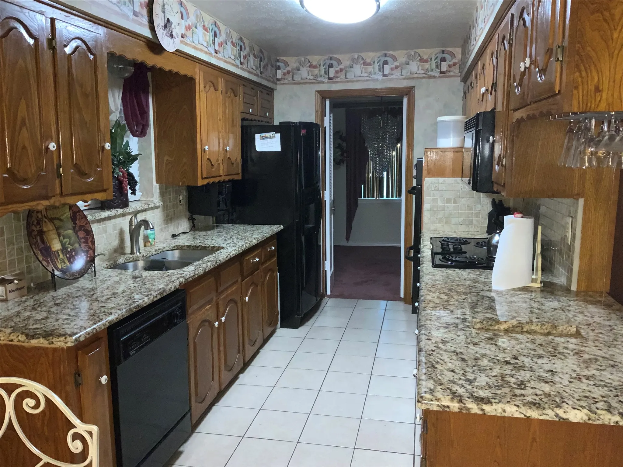 Kitchen featuring wood cabinetry, granite-finish countertops, tile backsplash, and a tile floor