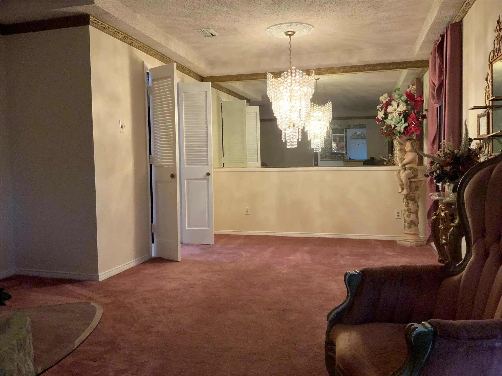 Wall-to-wall carpeting, decorative wall molding, crystal chandelier, and louvered bifold doors